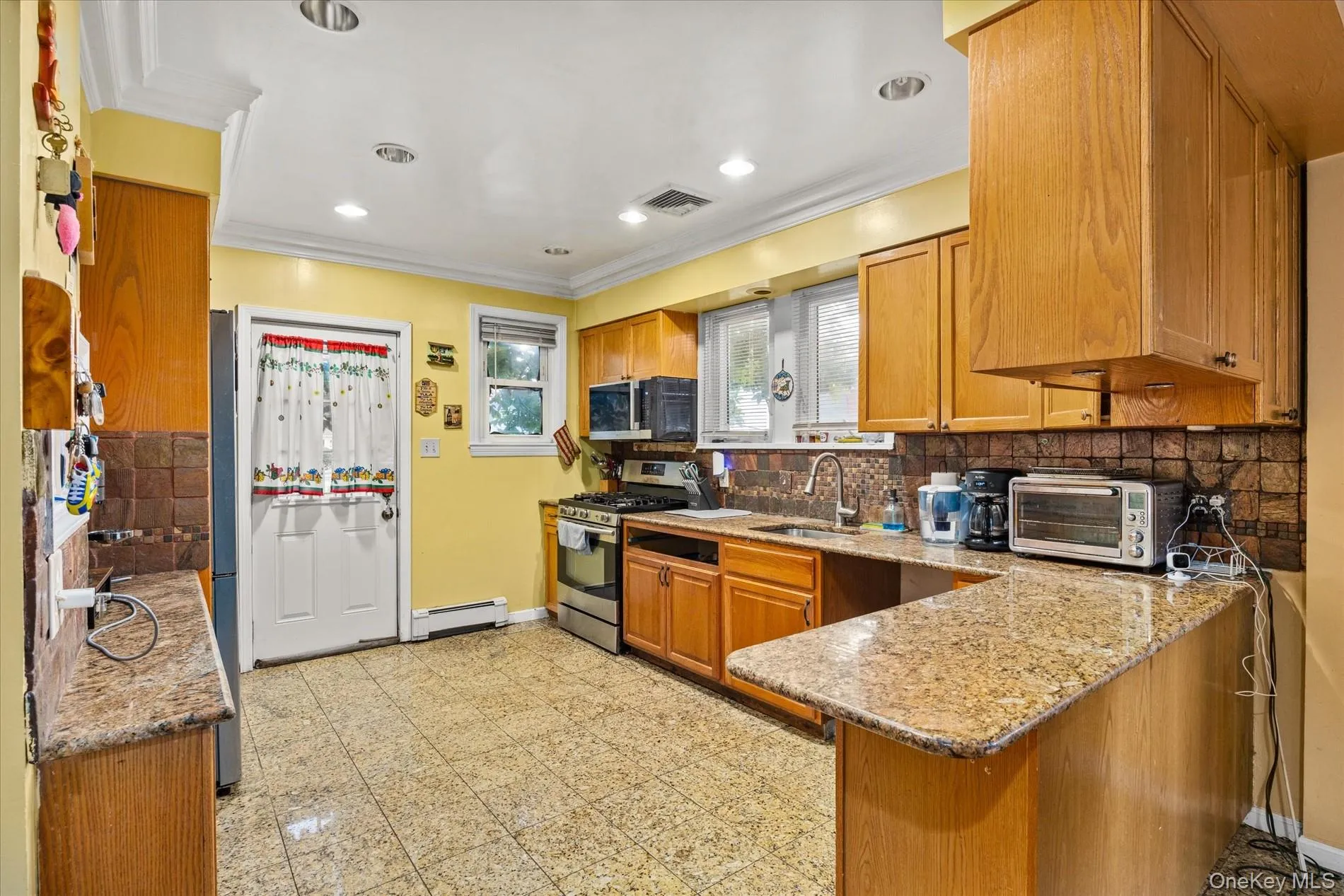 Kitchen featuring wood cabinetry, granite-finish countertops, tile backsplash, stainless steel appliances, and recessed lighting Kitchen featuring wood cabinetry, granite-finish countertops, tile backsplash, stainless steel appliances, and recessed lighting