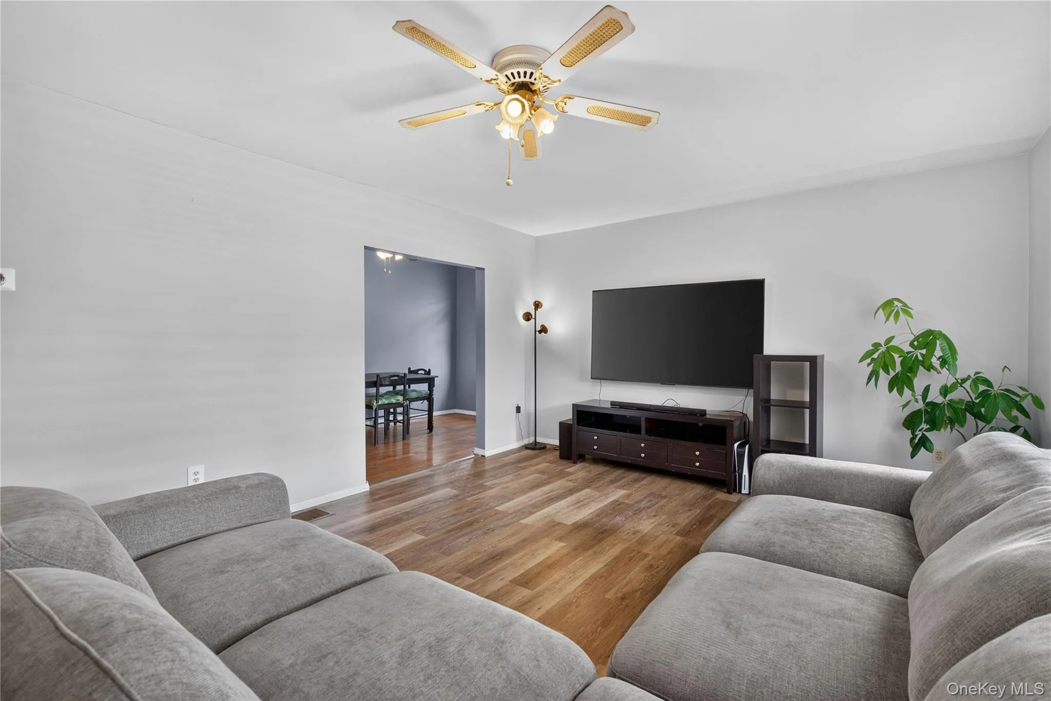 Wood-finish flooring throughout, with a ceiling fan light fixture and a wide doorway Wood-finish flooring throughout, with a ceiling fan light fixture and a wide doorway
