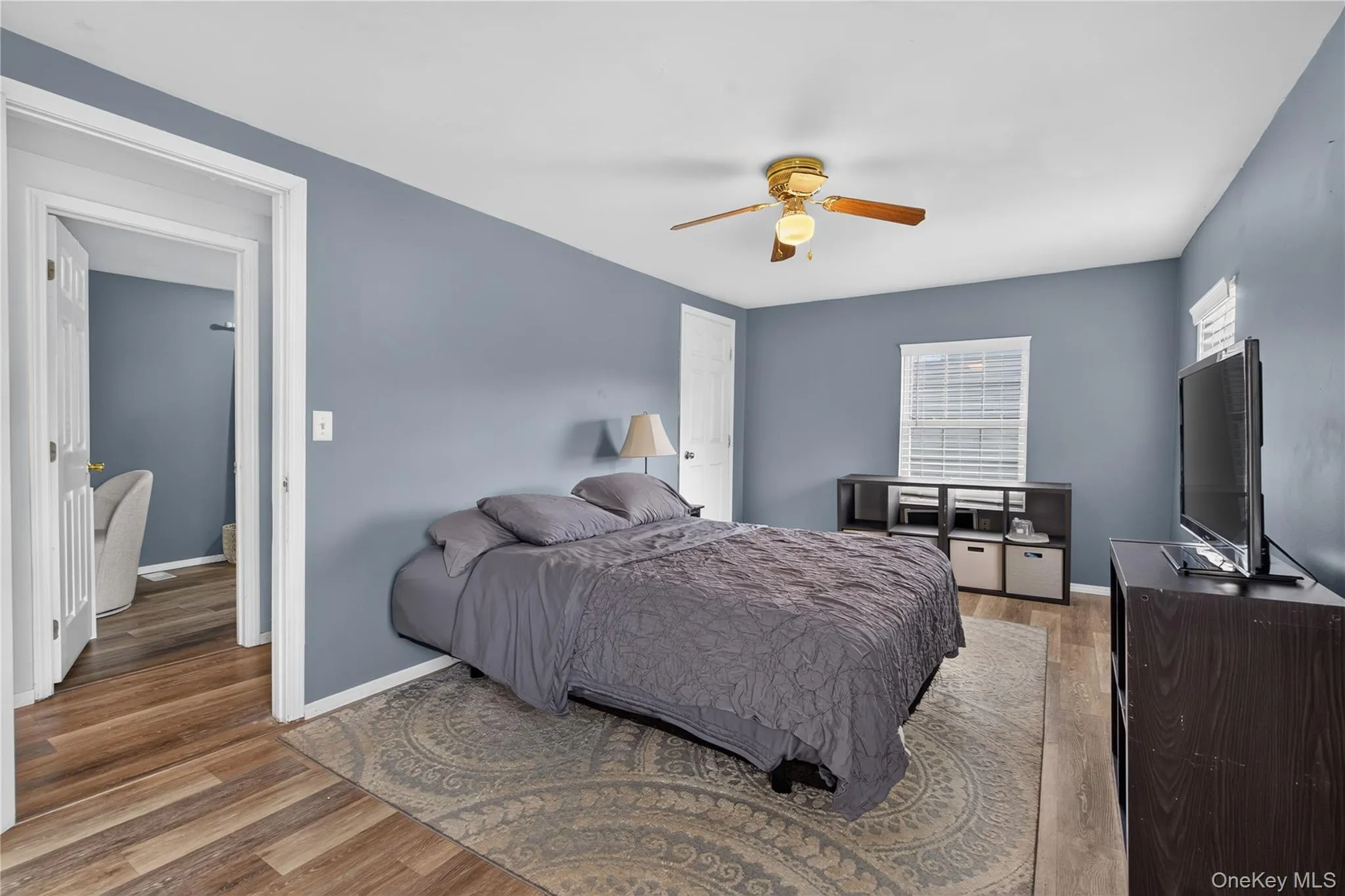 Wood-finish flooring, ceiling fan with integrated lighting, and a white window blind Wood-finish flooring, ceiling fan with integrated lighting, and a white window blind
