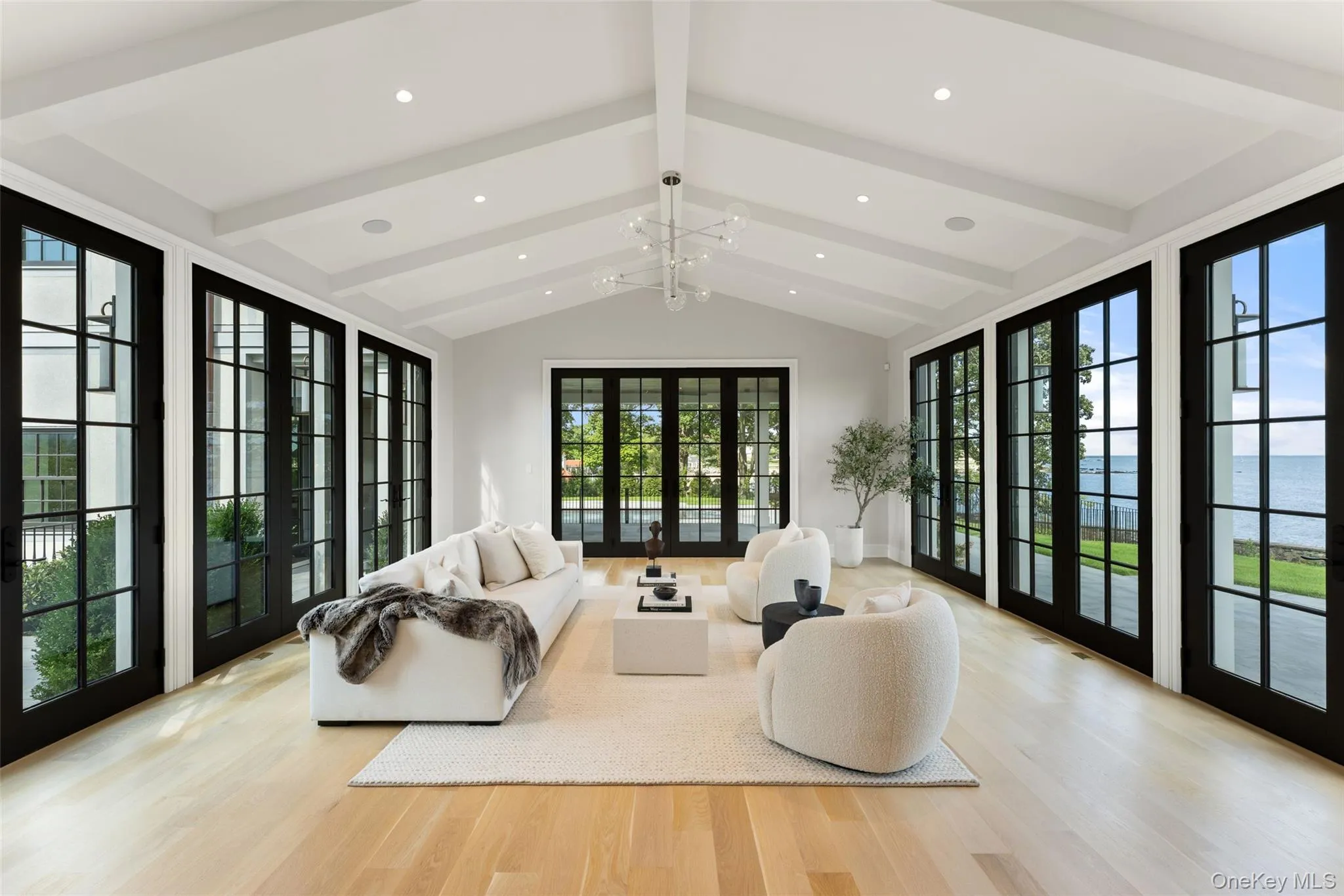 Expansive waterfront living room framed by oversized windows and glass doors. Expansive waterfront living room framed by oversized windows and glass doors.