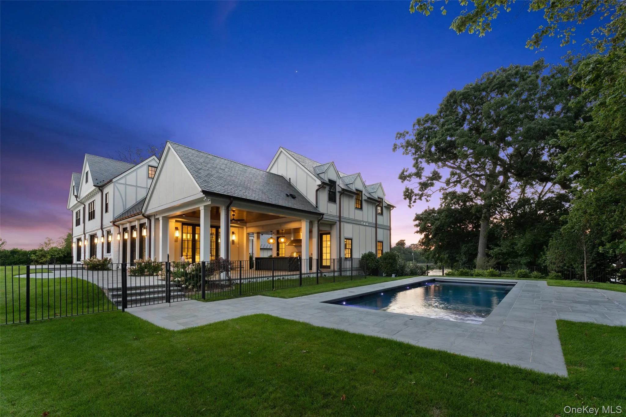 Poolside at twilight, with the covered outdoor living spaces glowing against the evening sky. Poolside at twilight, with the covered outdoor living spaces glowing against the evening sky.
