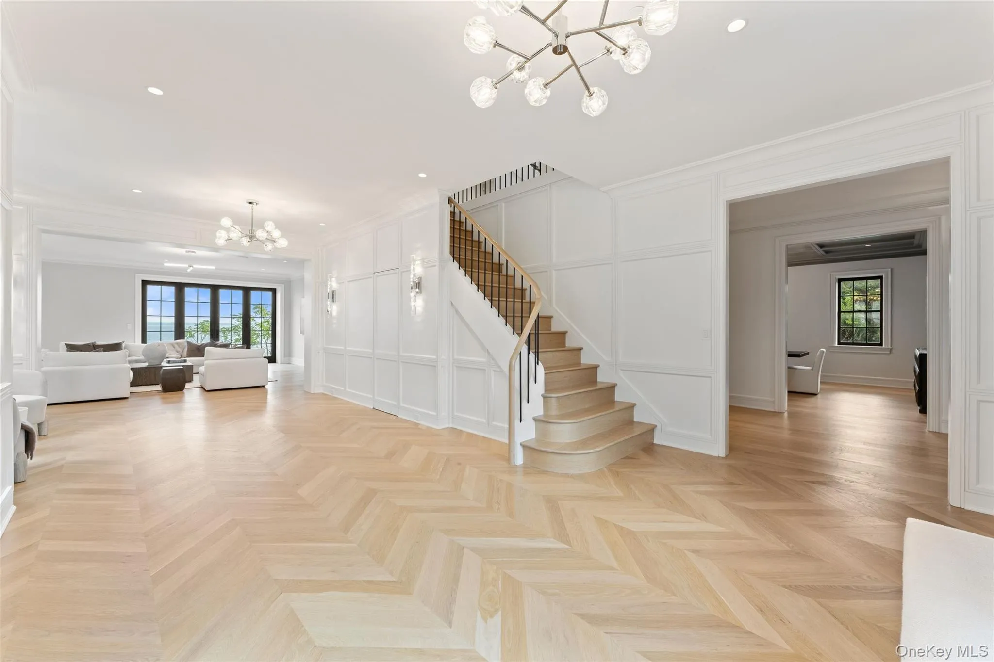 Dramatic entry gallery with herringbone white oak floors, paneled walls and a sculptural stair. Dramatic entry gallery with herringbone white oak floors, paneled walls and a sculptural stair.
