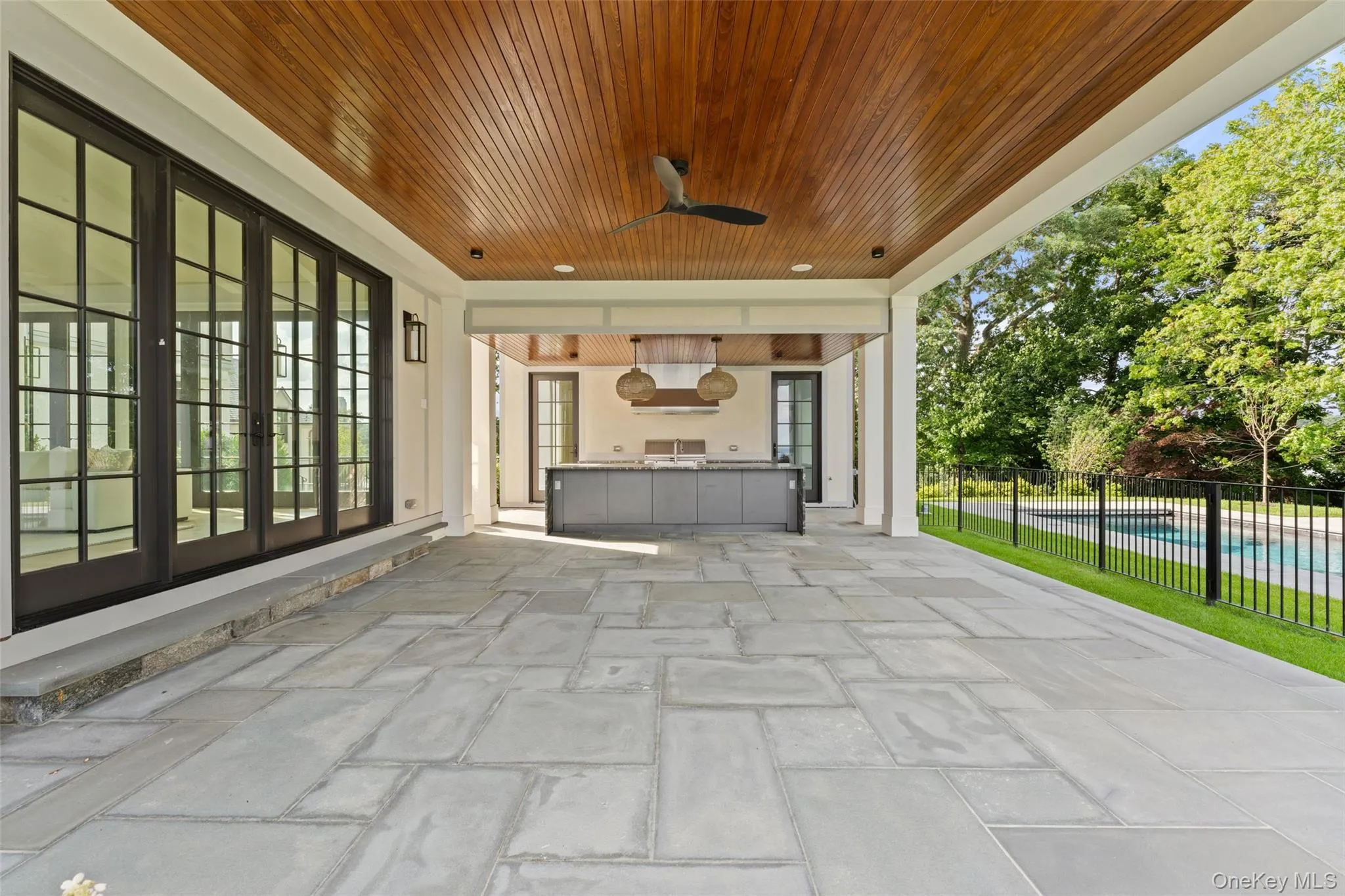 Outdoor Covered bluestone terrace with wood-paneled ceiling and seamless access to the outdoor kitchen Outdoor Covered bluestone terrace with wood-paneled ceiling and seamless access to the outdoor kitchen
