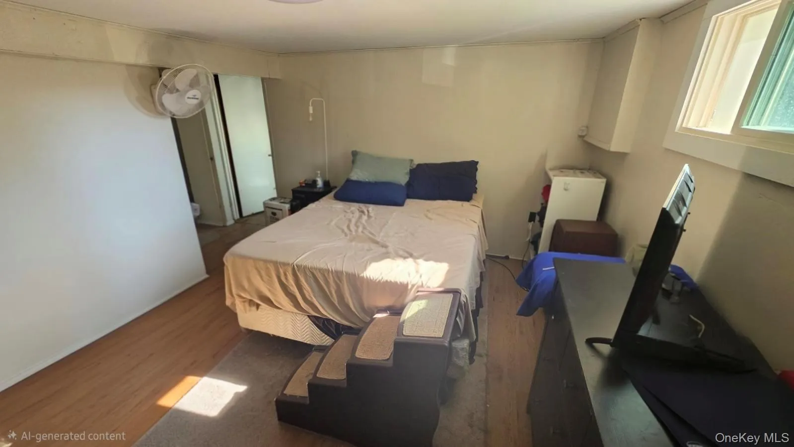 Interior space with wood-finish flooring, a single window, and neutral-toned walls Interior space with wood-finish flooring, a single window, and neutral-toned walls