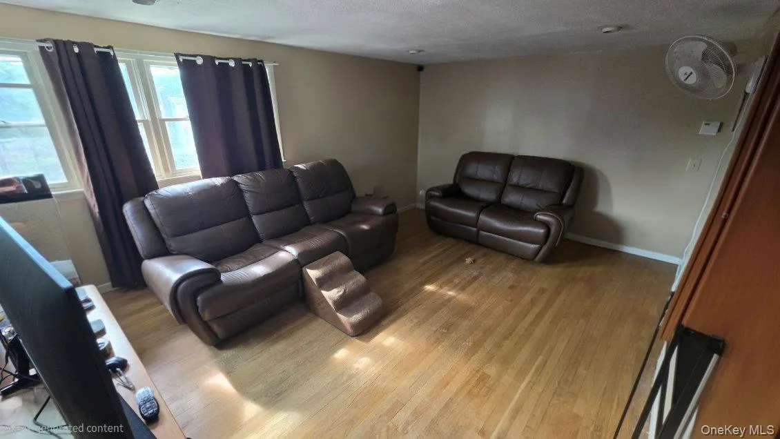 Spacious living area showcasing wood-finish flooring, large windows . Spacious living area showcasing wood-finish flooring, large windows .