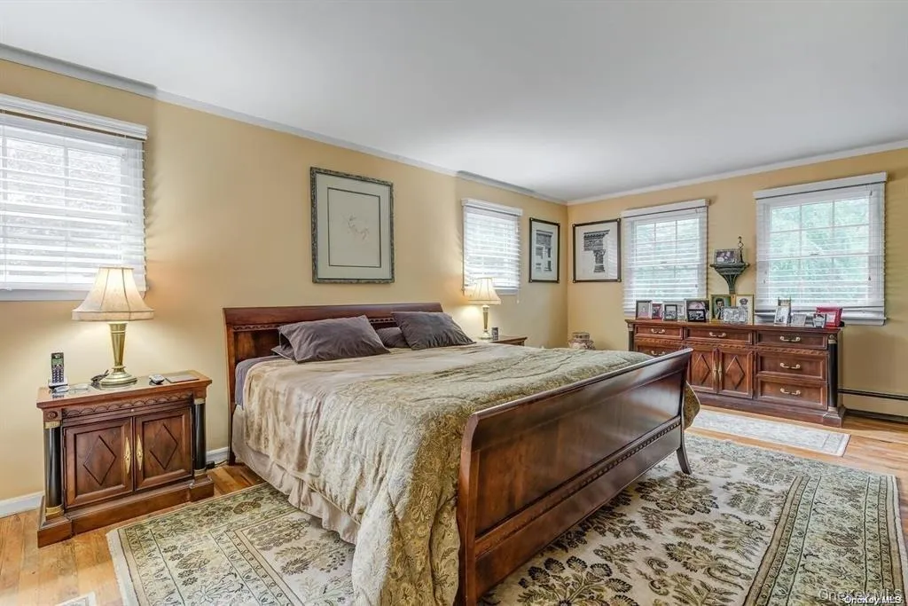 Bedroom with ornamental molding, light wood-type flooring, and baseboard heating Bedroom with ornamental molding, light wood-type flooring, and baseboard heating