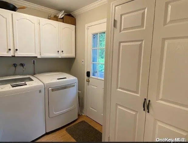 Laundry room with cabinet space, washer and dryer, ornamental molding, and light wood-style floors Laundry room with cabinet space, washer and dryer, ornamental molding, and light wood-style floors
