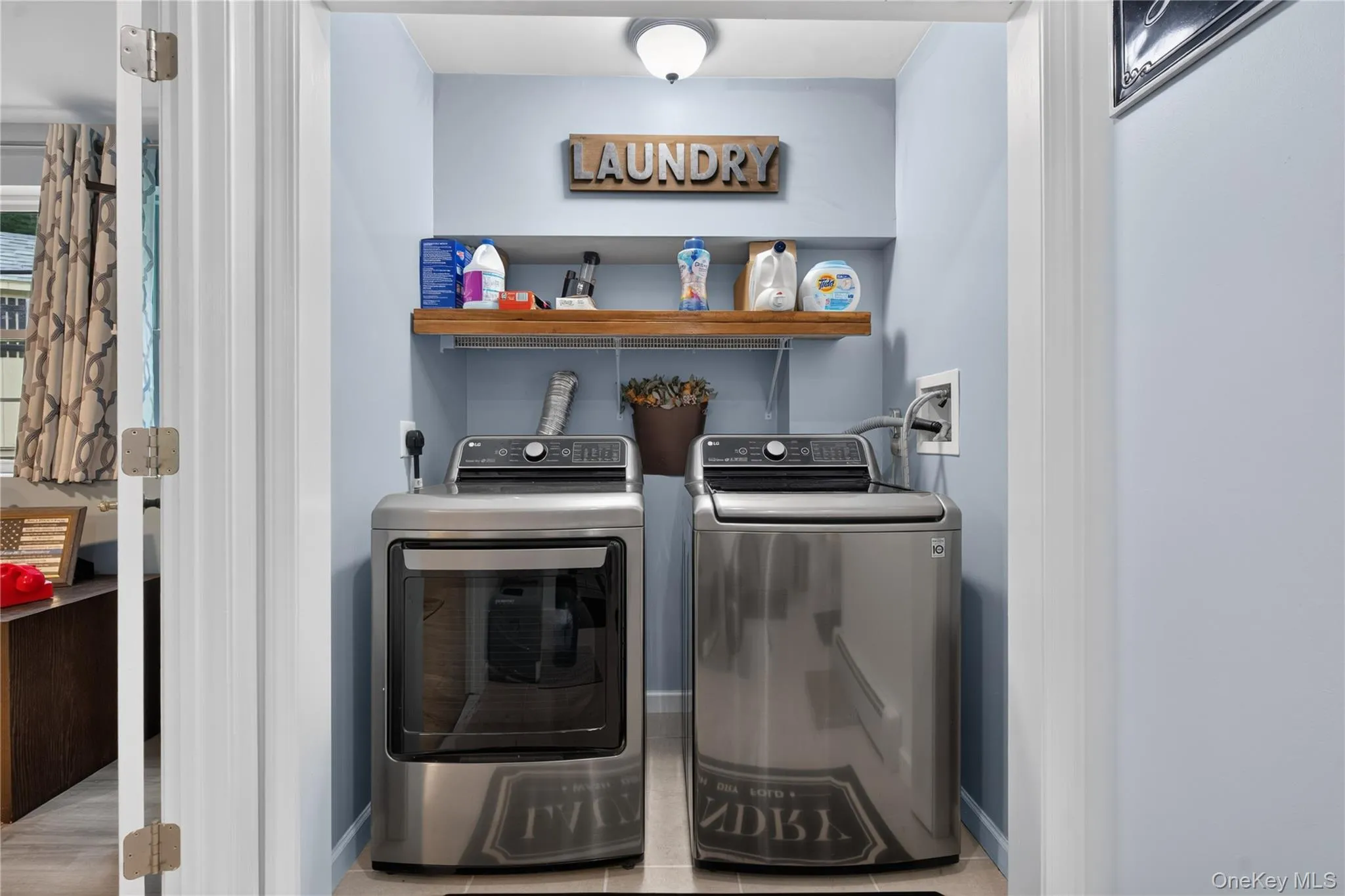 Dedicated laundry area featuring a built-in wood shelf and overhead lighting Dedicated laundry area featuring a built-in wood shelf and overhead lighting