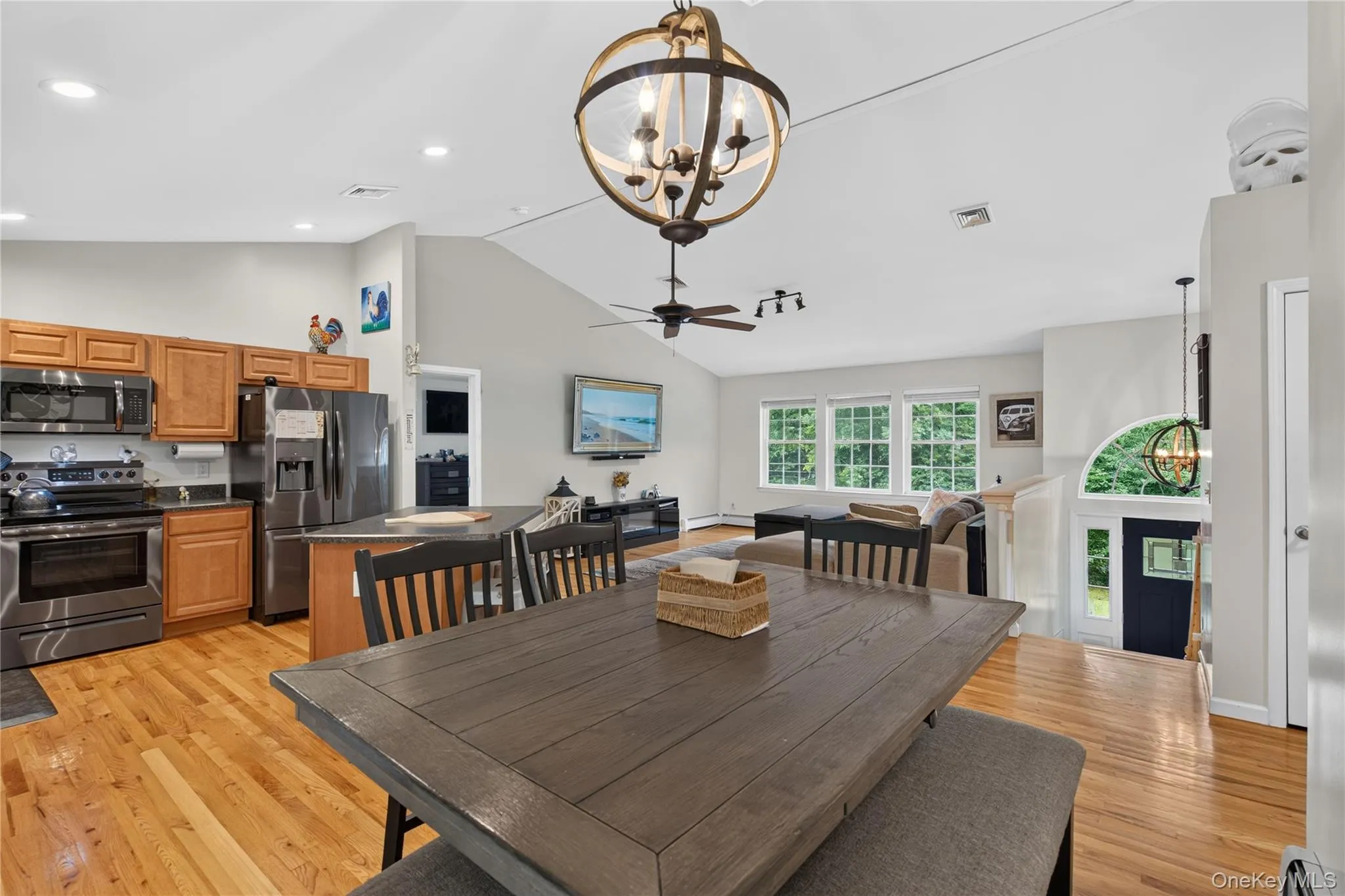 Vaulted ceiling, wood-finish flooring, stainless steel appliances, kitchen island with dark countertop, multiple windows Vaulted ceiling, wood-finish flooring, stainless steel appliances, kitchen island with dark countertop, multiple windows