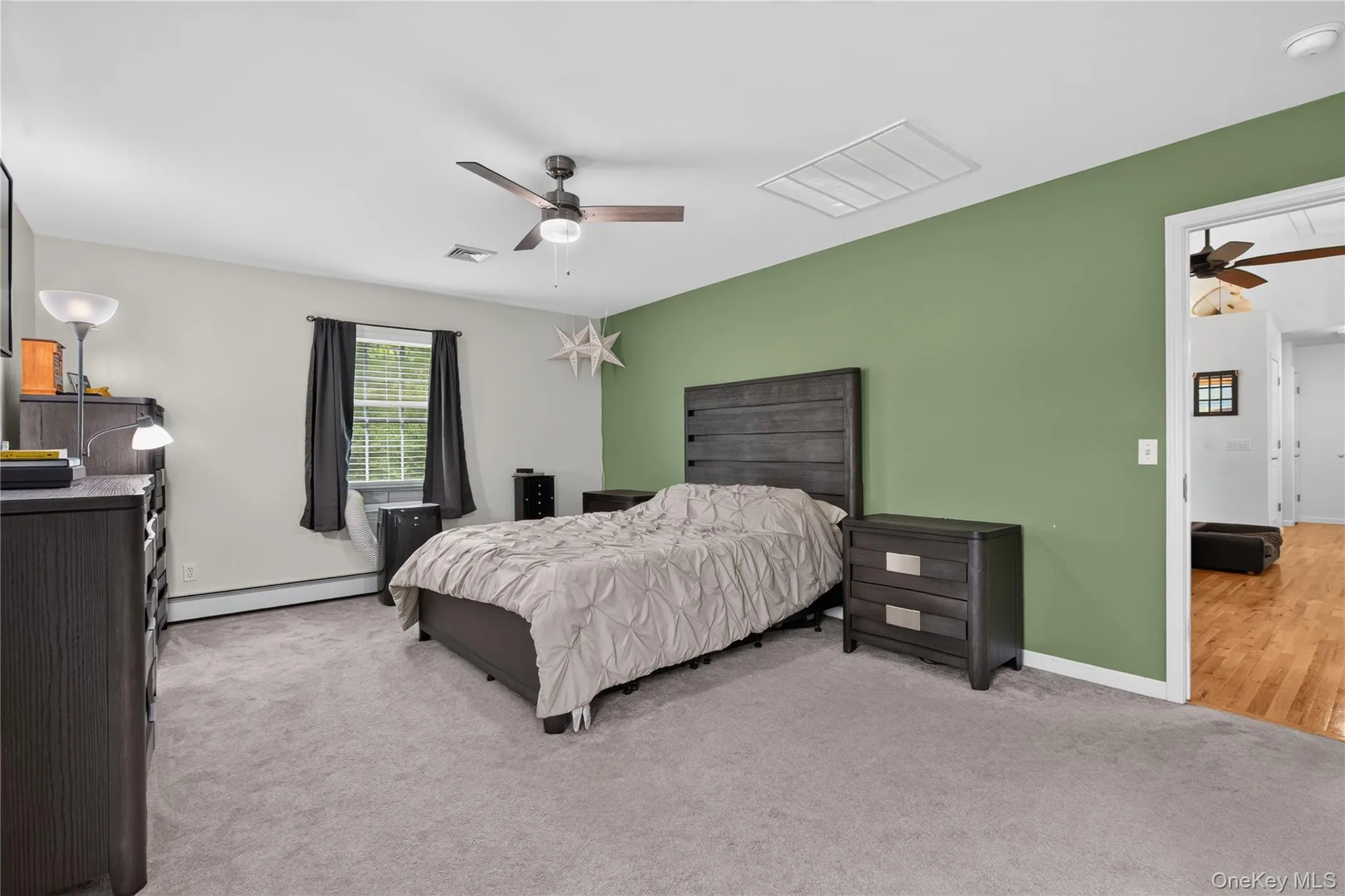 Wall-to-wall carpeting, window with blinds, ceiling fan with integrated lighting, and a doorway leading to wood-finish flooring Wall-to-wall carpeting, window with blinds, ceiling fan with integrated lighting, and a doorway leading to wood-finish flooring