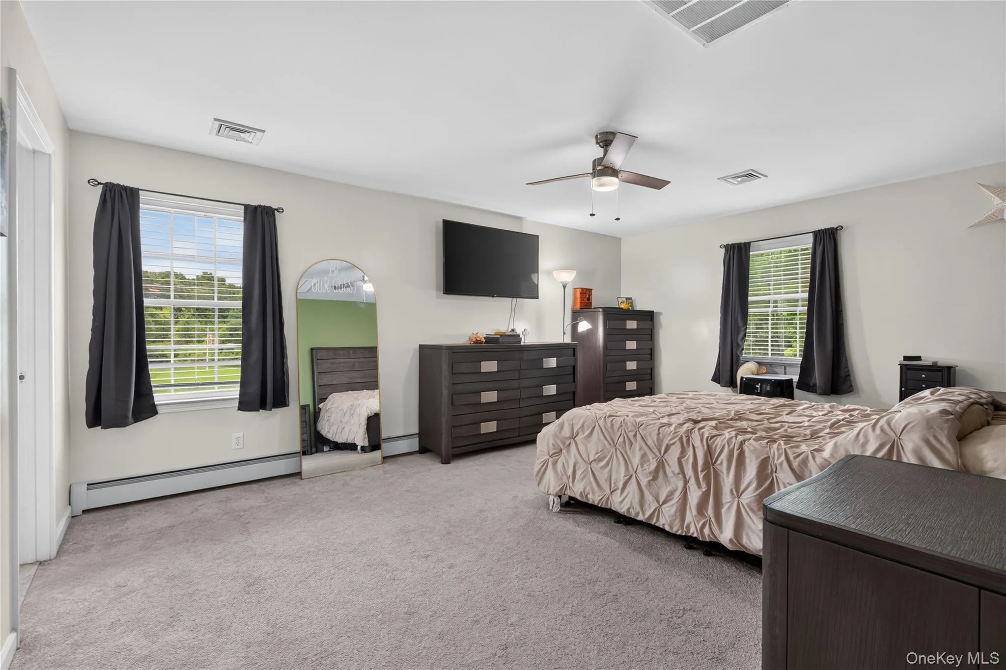 Spacious room featuring light-colored walls, carpeted flooring, and a ceiling fan with integrated lighting Spacious room featuring light-colored walls, carpeted flooring, and a ceiling fan with integrated lighting