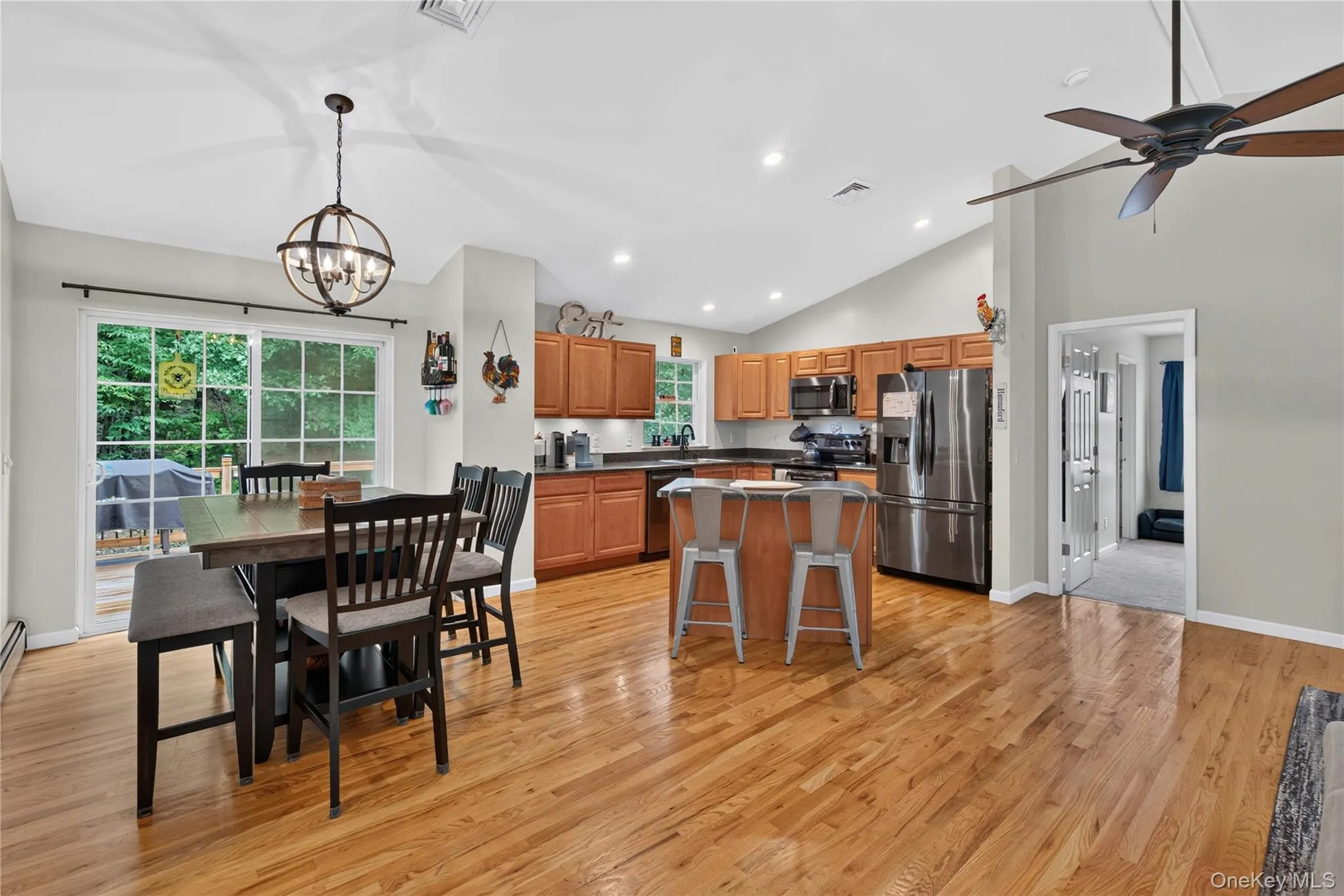 Kitchen and dining area with hardwood flooring, vaulted ceiling, and sliding glass doors Kitchen and dining area with hardwood flooring, vaulted ceiling, and sliding glass doors