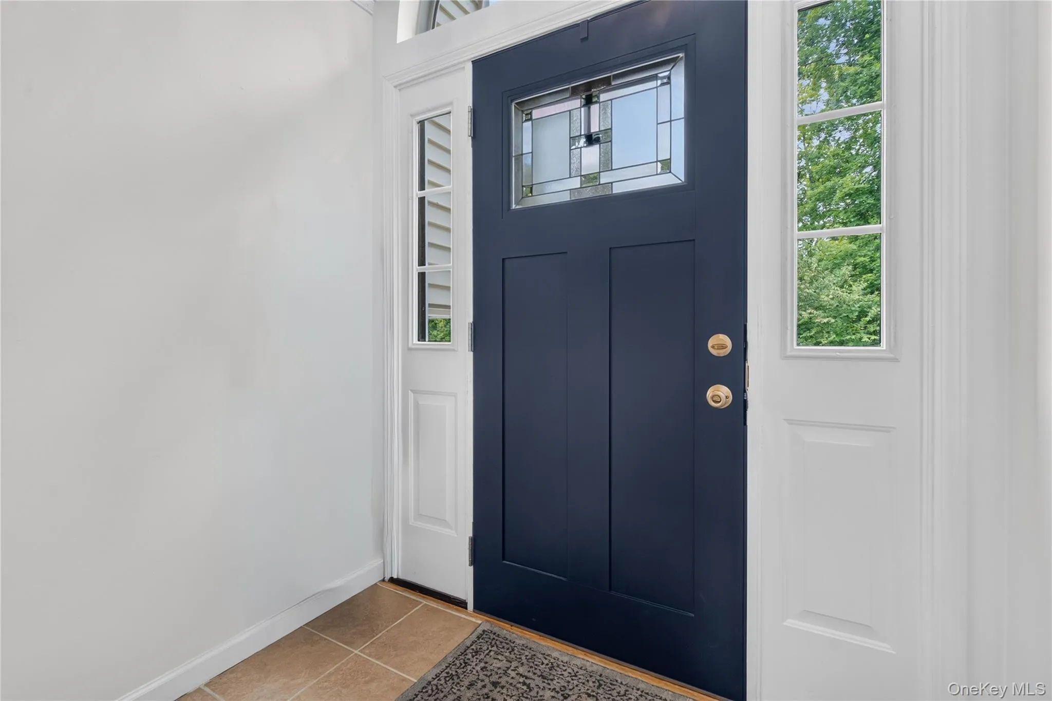 Navy blue entry door with decorative glass inlay, flanked by two sidelight windows Navy blue entry door with decorative glass inlay, flanked by two sidelight windows