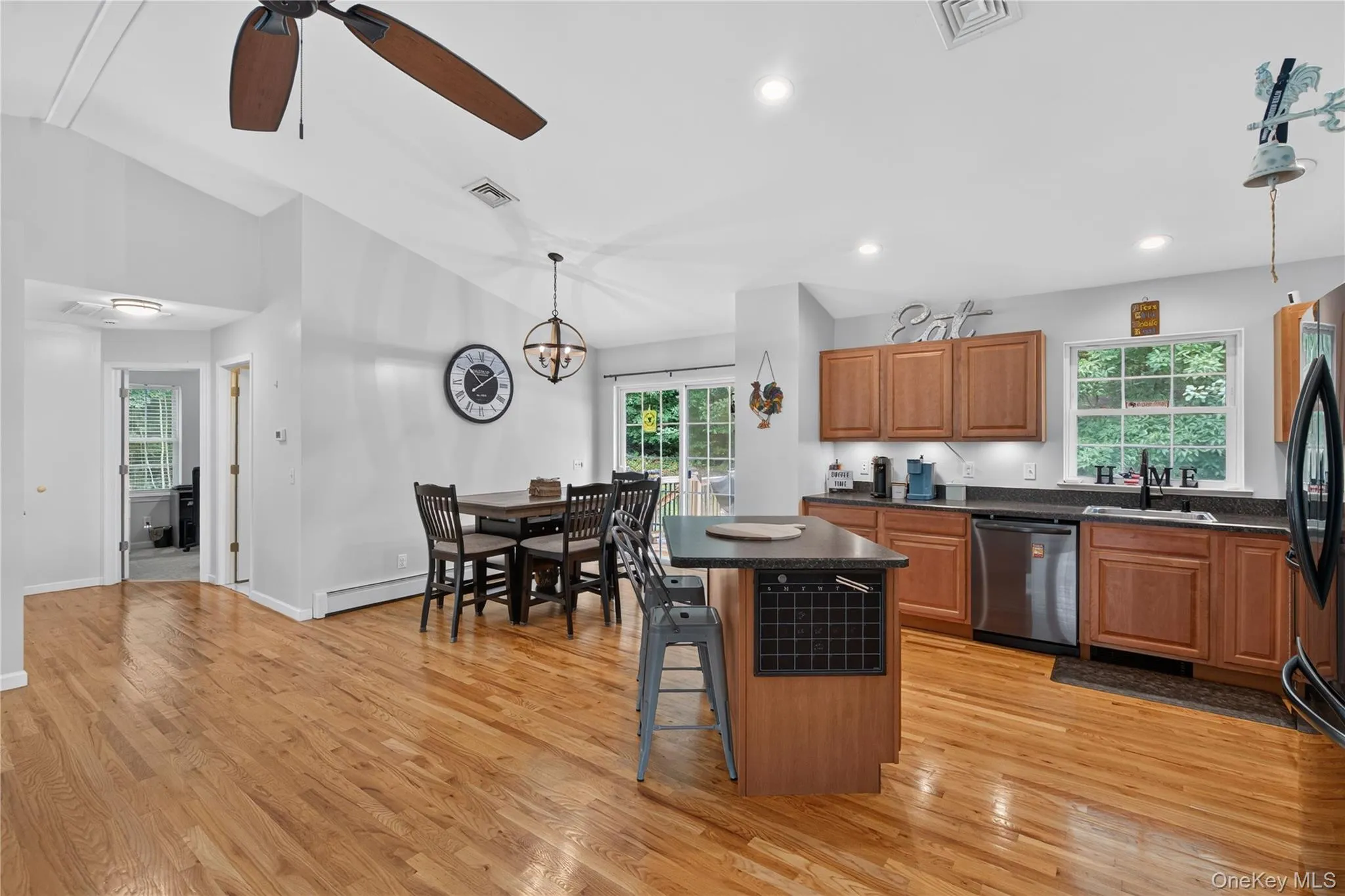 Kitchen and dining area featuring wood-finish flooring, recessed lighting, wood cabinetry, stainless steel appliances, and a central island with a breakfast bar Kitchen and dining area featuring wood-finish flooring, recessed lighting, wood cabinetry, stainless steel appliances, and a central island with a breakfast bar