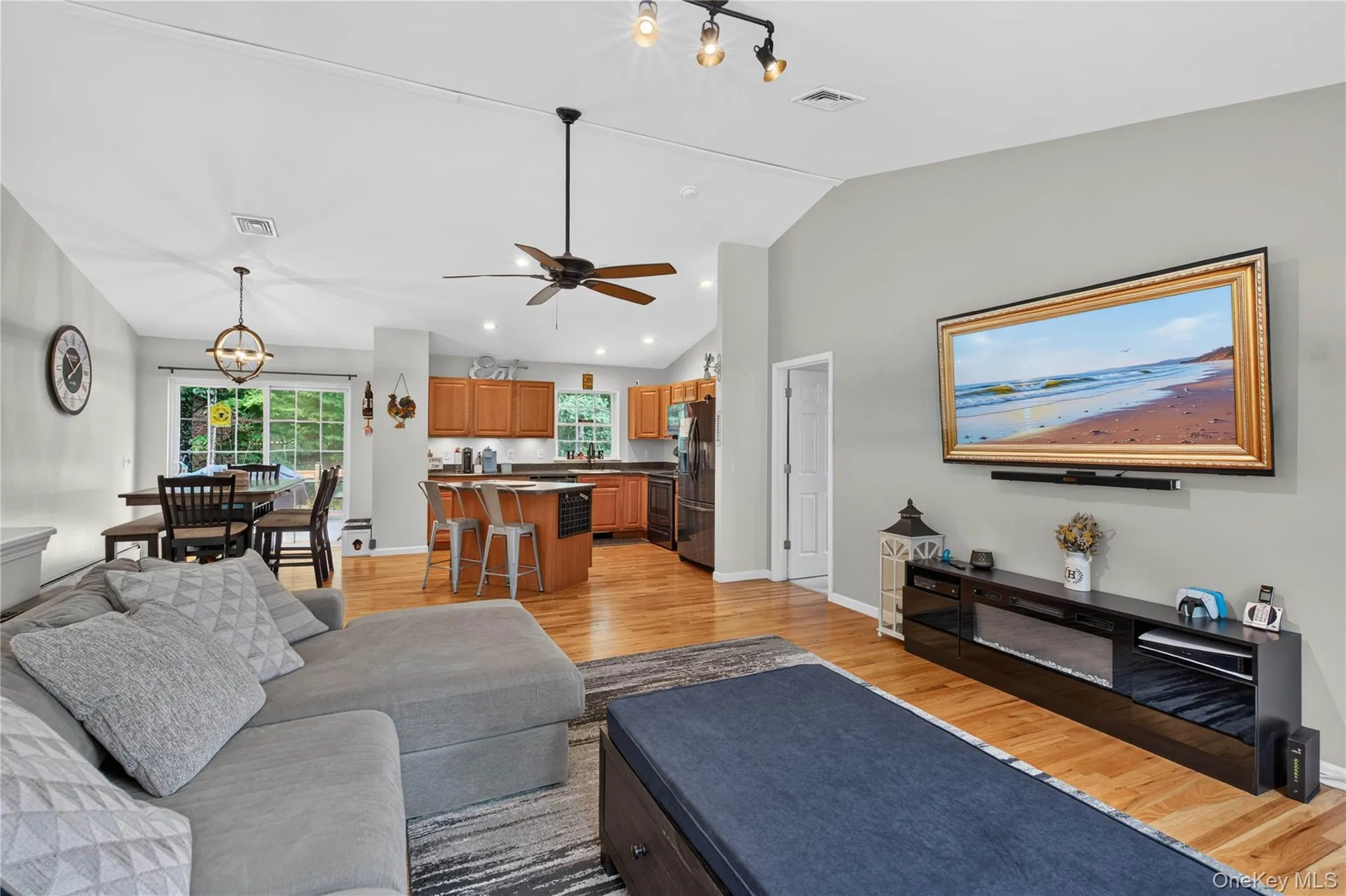 Open-concept living area with vaulted ceiling, wood-finish flooring, and recessed lighting Open-concept living area with vaulted ceiling, wood-finish flooring, and recessed lighting