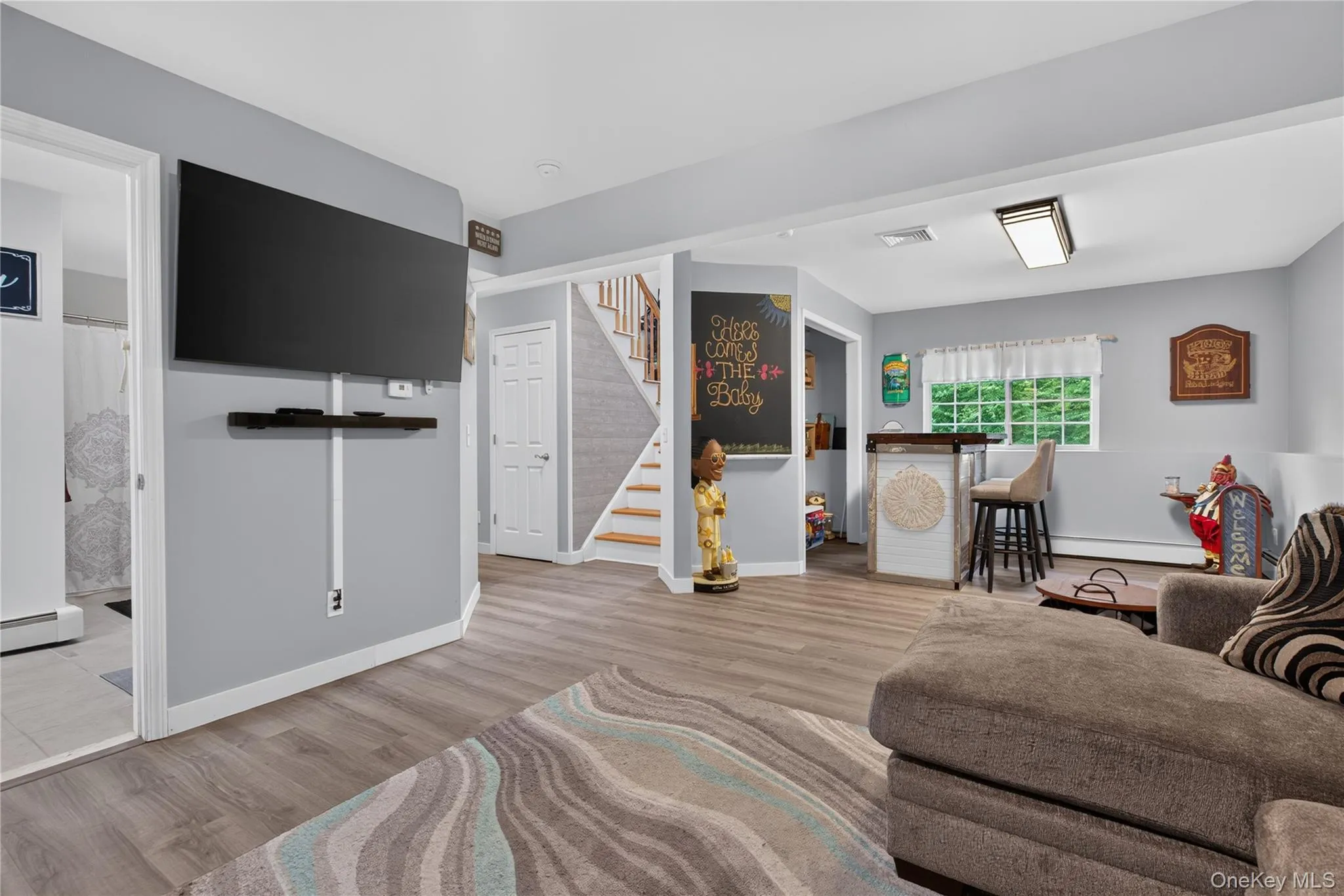 Wood-finish flooring throughout, wall-mounted display shelf, built-in bar, and staircase with wood treads Wood-finish flooring throughout, wall-mounted display shelf, built-in bar, and staircase with wood treads