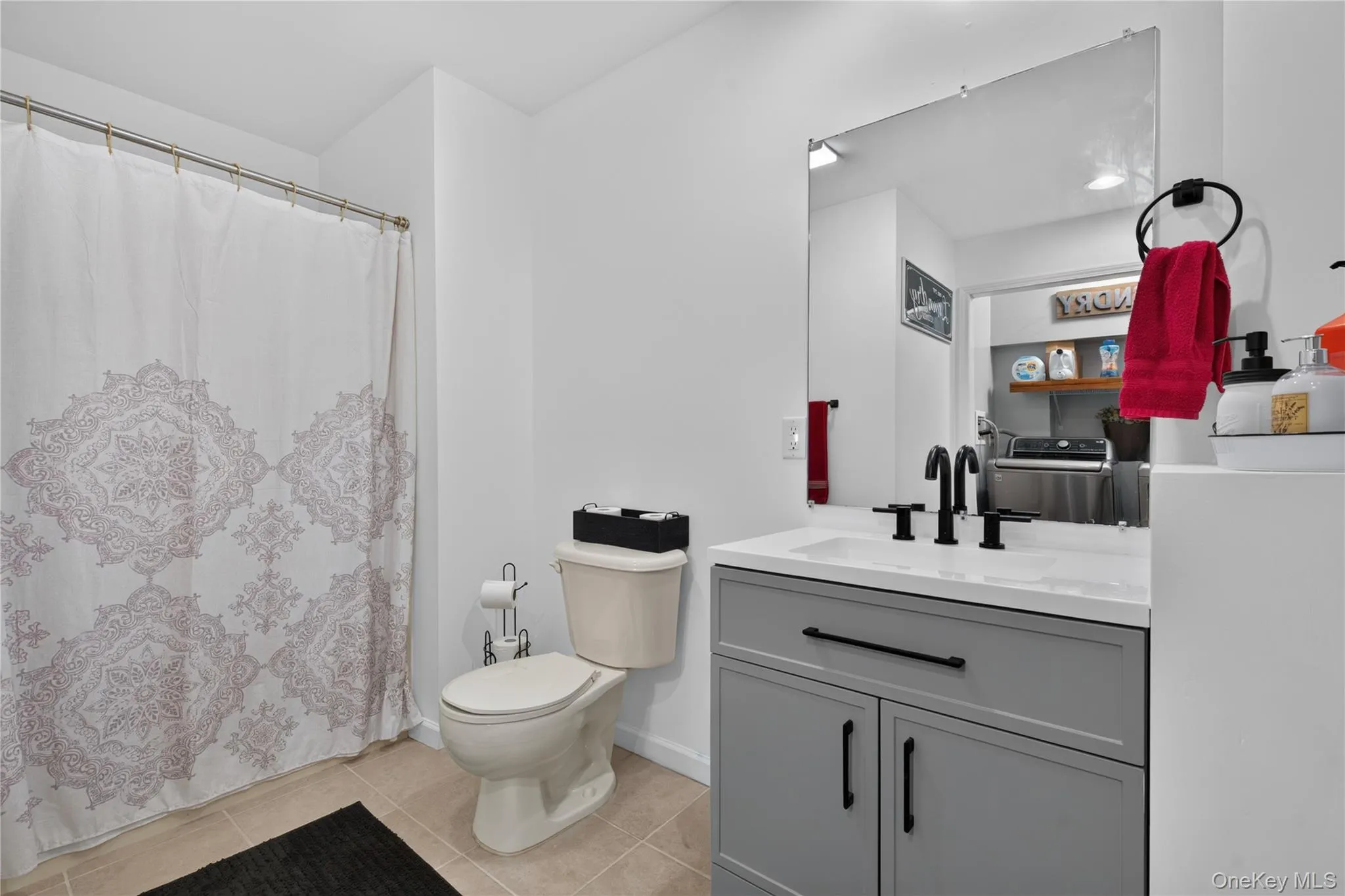 Modern vanity with a white countertop and matte black fixtures, tile flooring, and a built-in toilet Modern vanity with a white countertop and matte black fixtures, tile flooring, and a built-in toilet