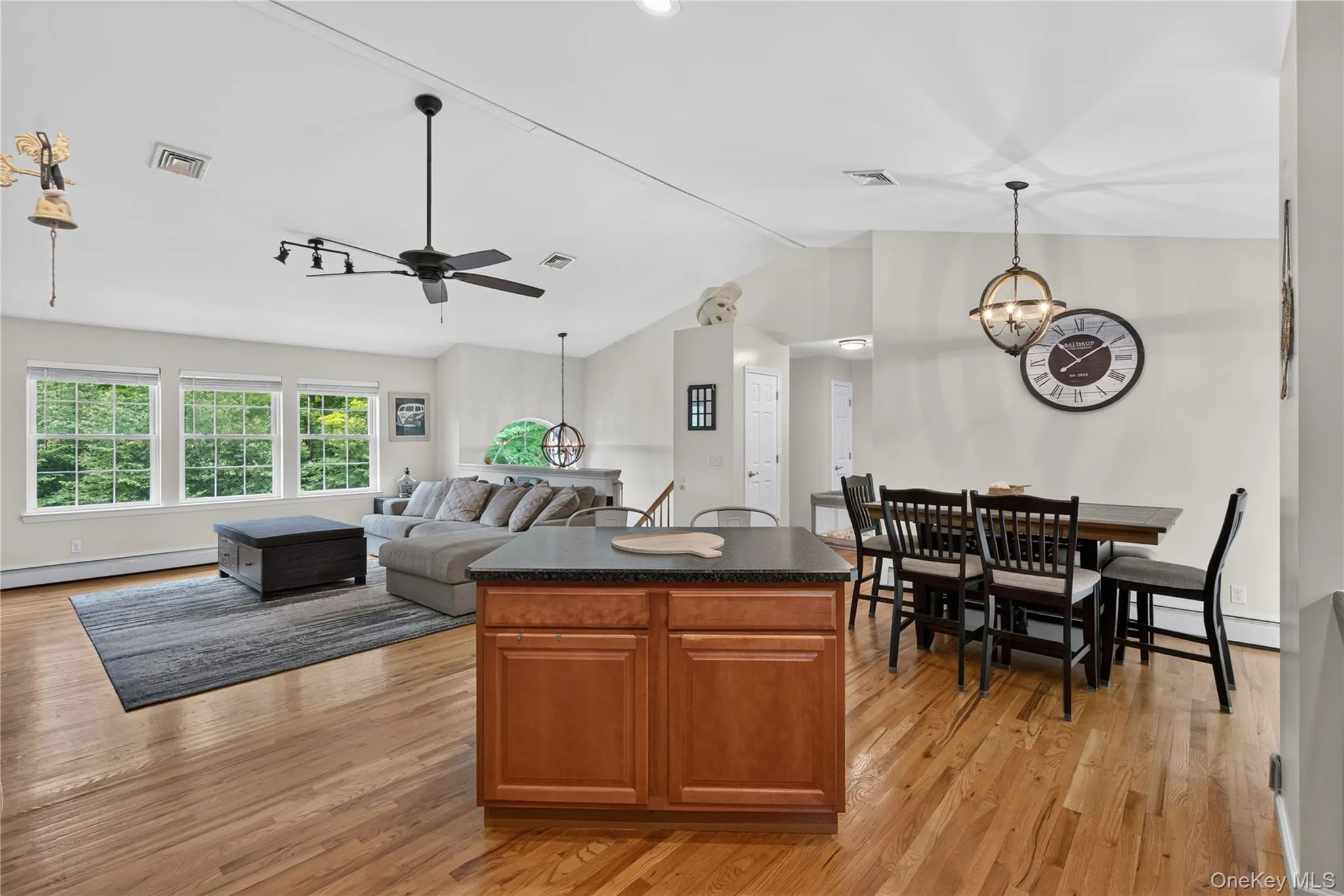 Wood-finished flooring, vaulted ceiling, kitchen island with dark counter top Wood-finished flooring, vaulted ceiling, kitchen island with dark counter top