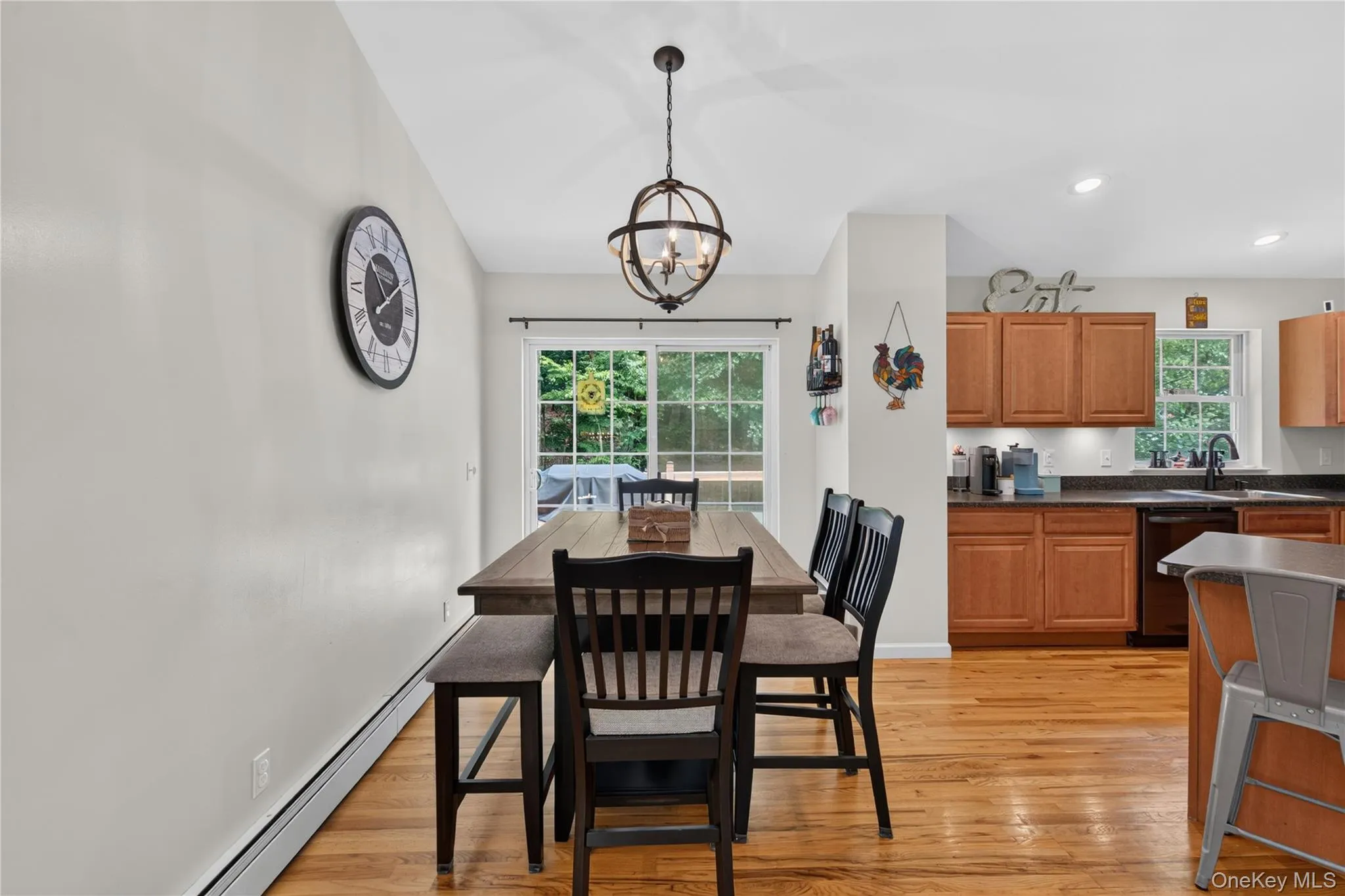 Expansive dining area featuring wood-finish flooring, a contemporary spherical chandelier, and sliding glass doors Expansive dining area featuring wood-finish flooring, a contemporary spherical chandelier, and sliding glass doors