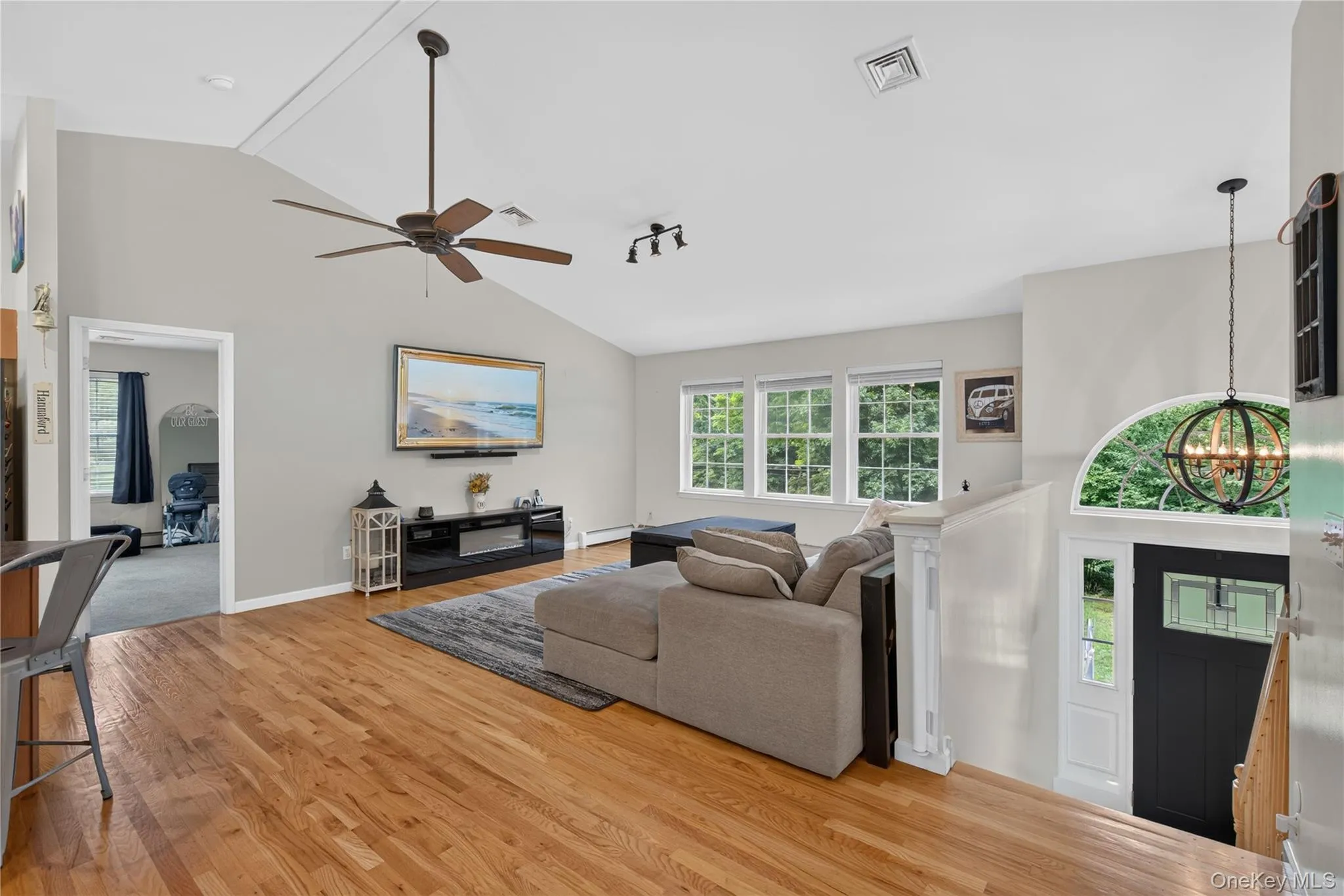 Hardwood flooring, vaulted ceiling, multiple windows, ceiling fan, and decorative light fixture Hardwood flooring, vaulted ceiling, multiple windows, ceiling fan, and decorative light fixture