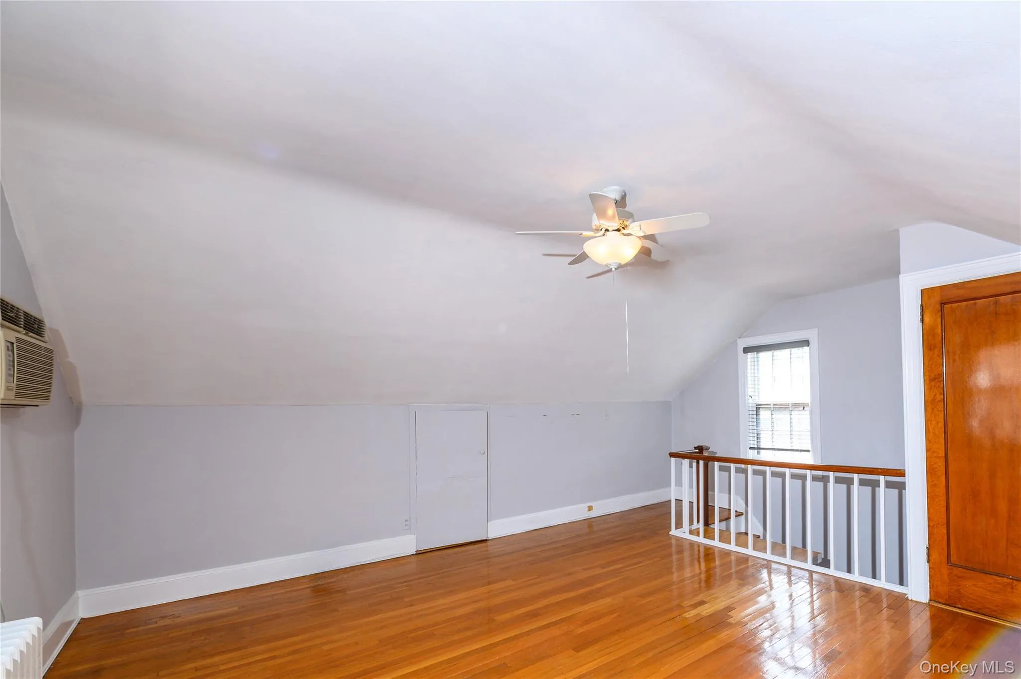 Wood-finish flooring with a ceiling fan, window, and railing Wood-finish flooring with a ceiling fan, window, and railing