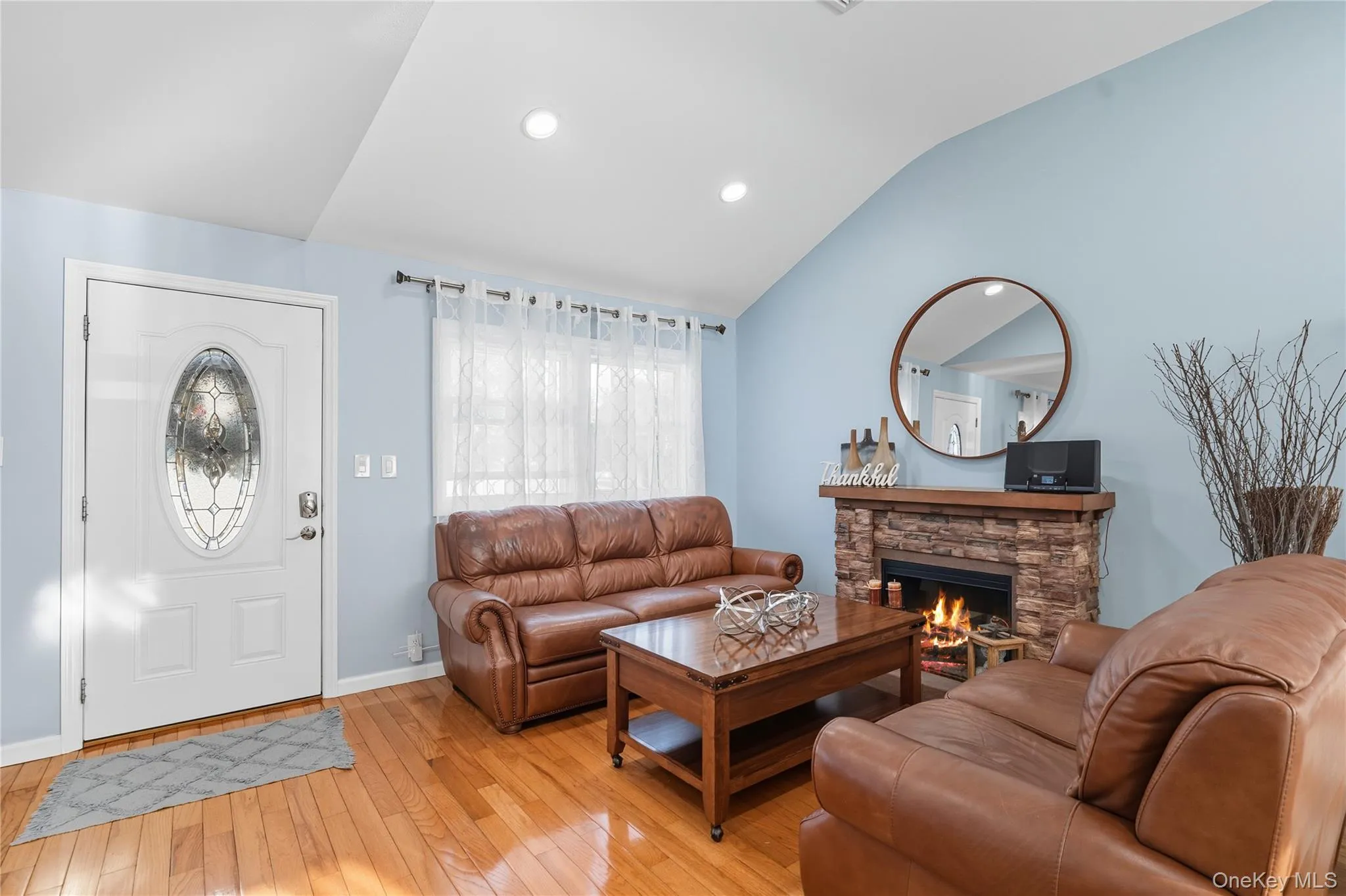 Living area with lofted ceiling, hardwood / wood-style floors, a fireplace, and recessed lighting Living area with lofted ceiling, hardwood / wood-style floors, a fireplace, and recessed lighting