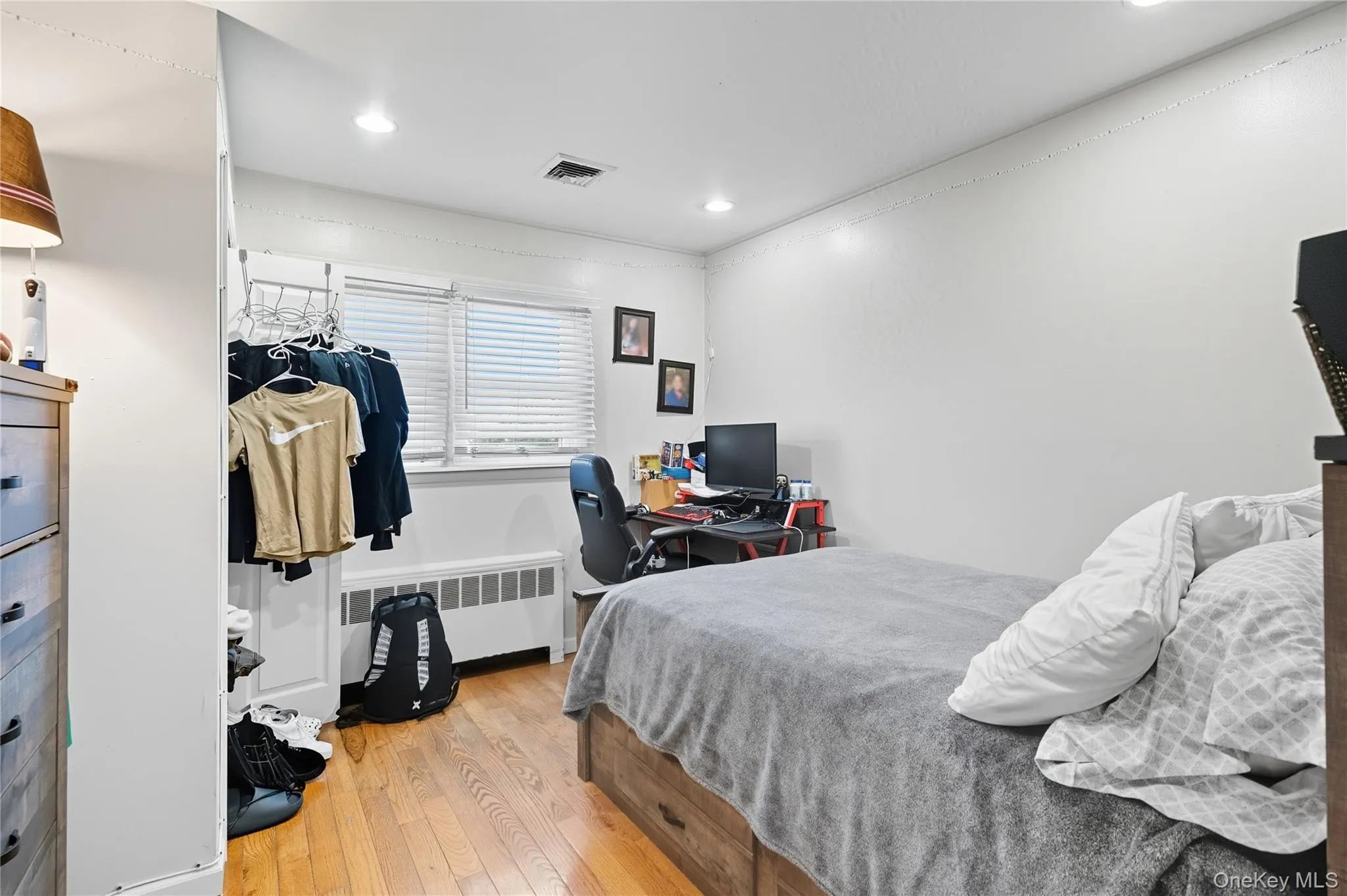 Bedroom with light wood-style floors, radiator heating unit, an office area, and recessed lighting Bedroom with light wood-style floors, radiator heating unit, an office area, and recessed lighting