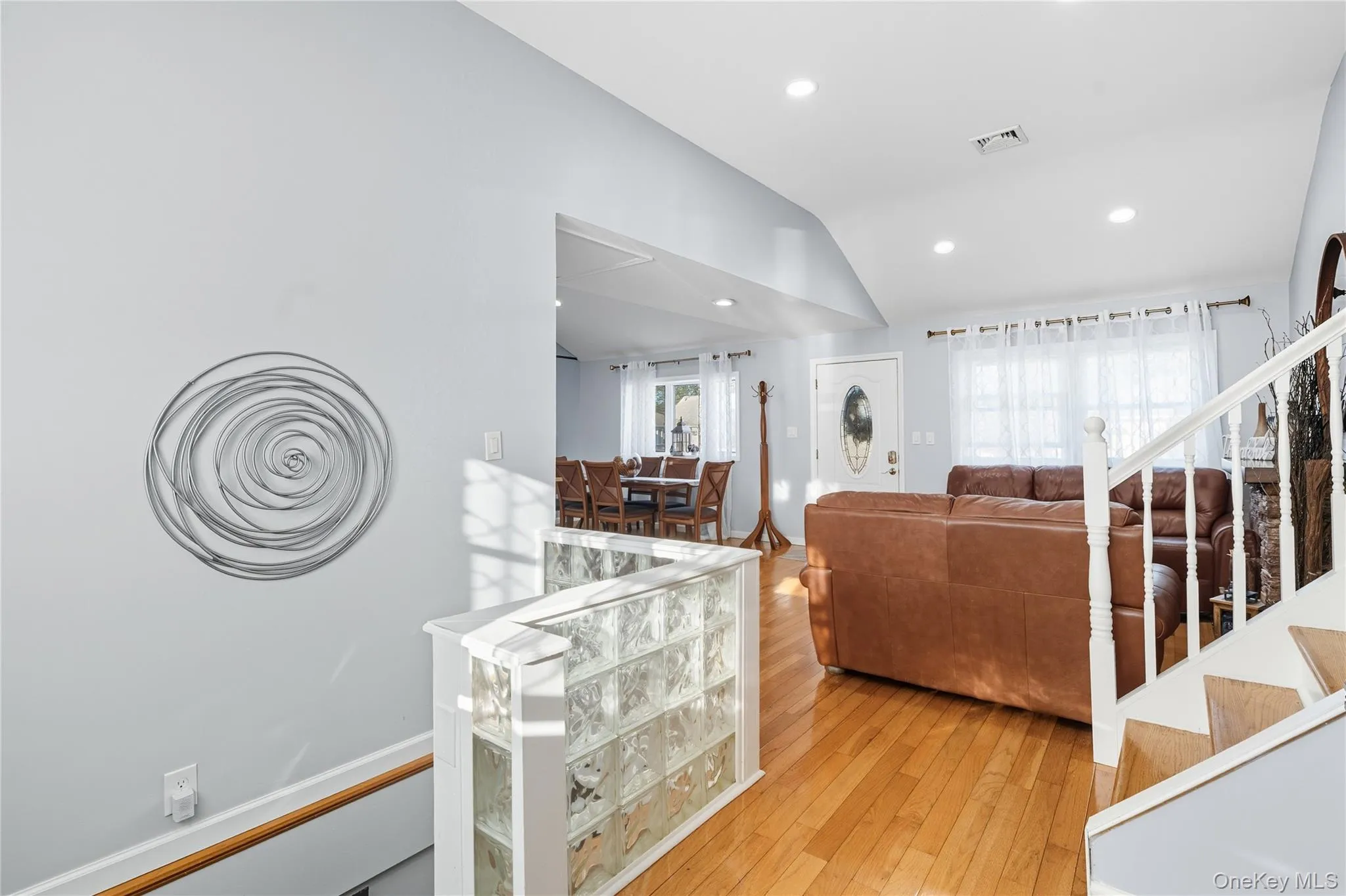 Living room featuring light wood-type flooring, vaulted ceiling, recessed lighting, and stairs Living room featuring light wood-type flooring, vaulted ceiling, recessed lighting, and stairs