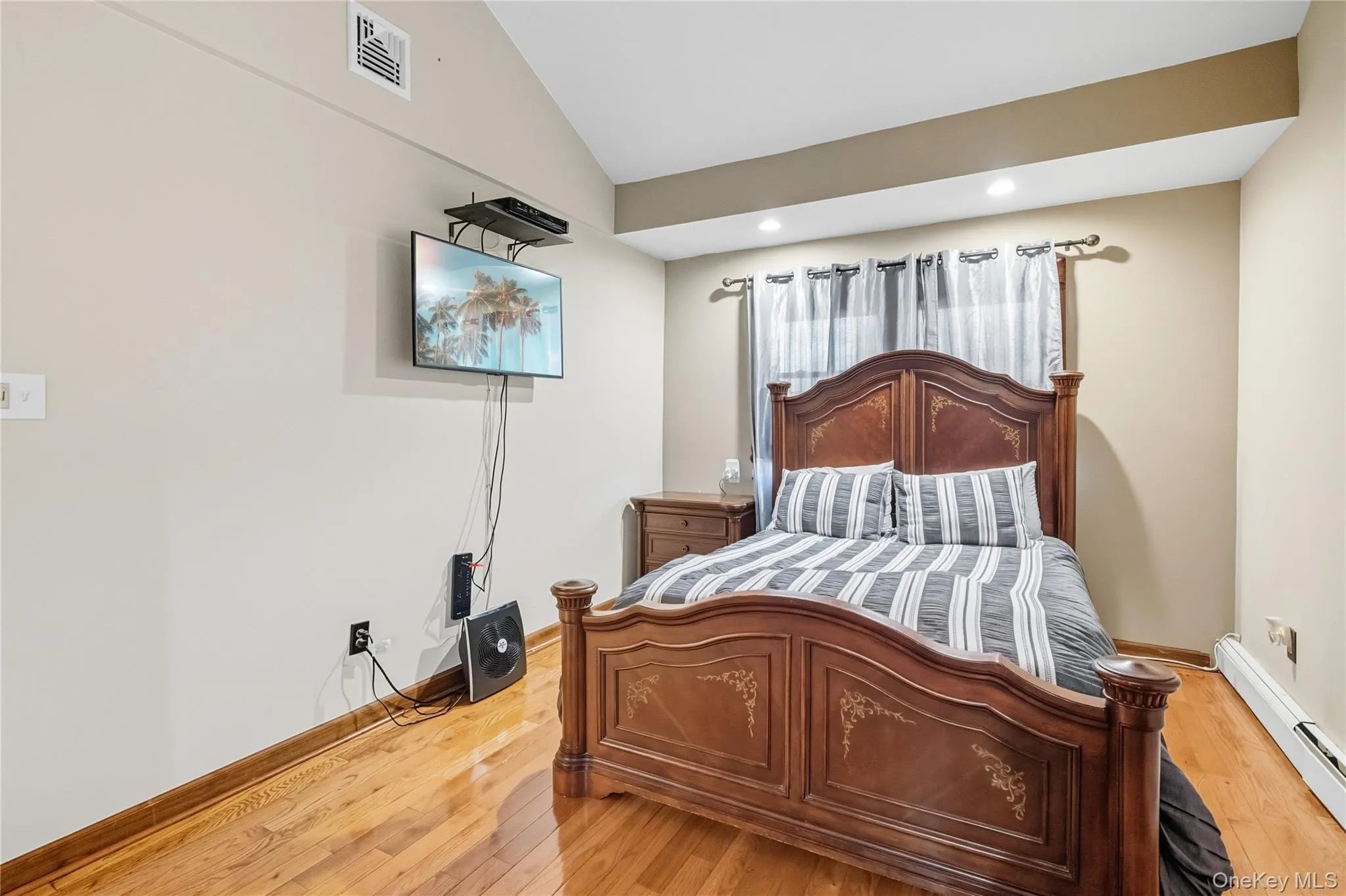 Bedroom with lofted ceiling, a baseboard radiator, light wood-style flooring, and recessed lighting Bedroom with lofted ceiling, a baseboard radiator, light wood-style flooring, and recessed lighting