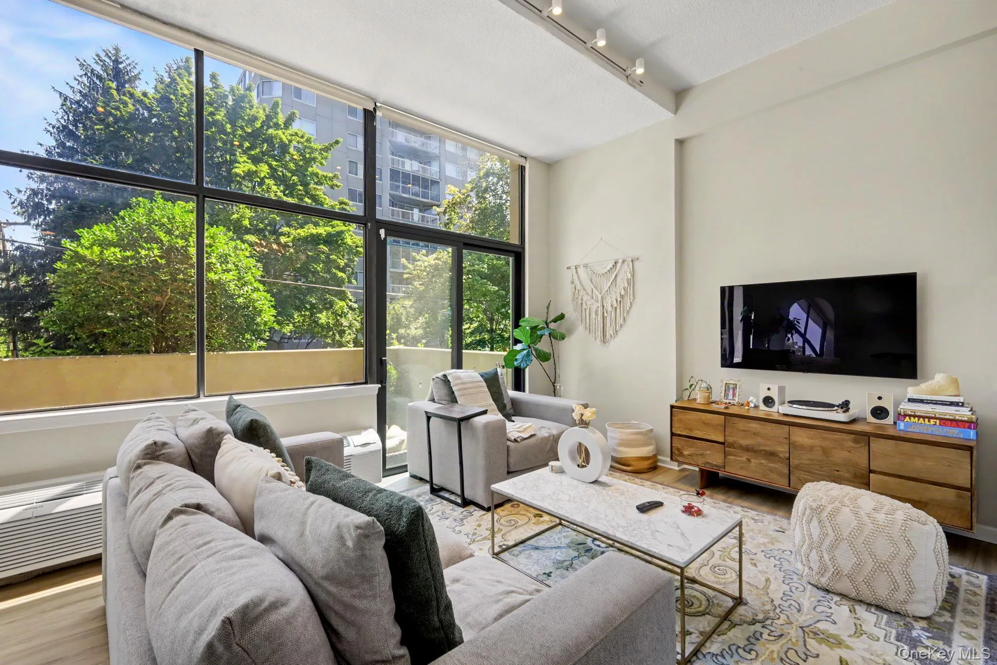 The spacious living room is defined by soaring ceilings and a dramatic wall of glass, filling the space with natural light. The spacious living room is defined by soaring ceilings and a dramatic wall of glass, filling the space with natural light.