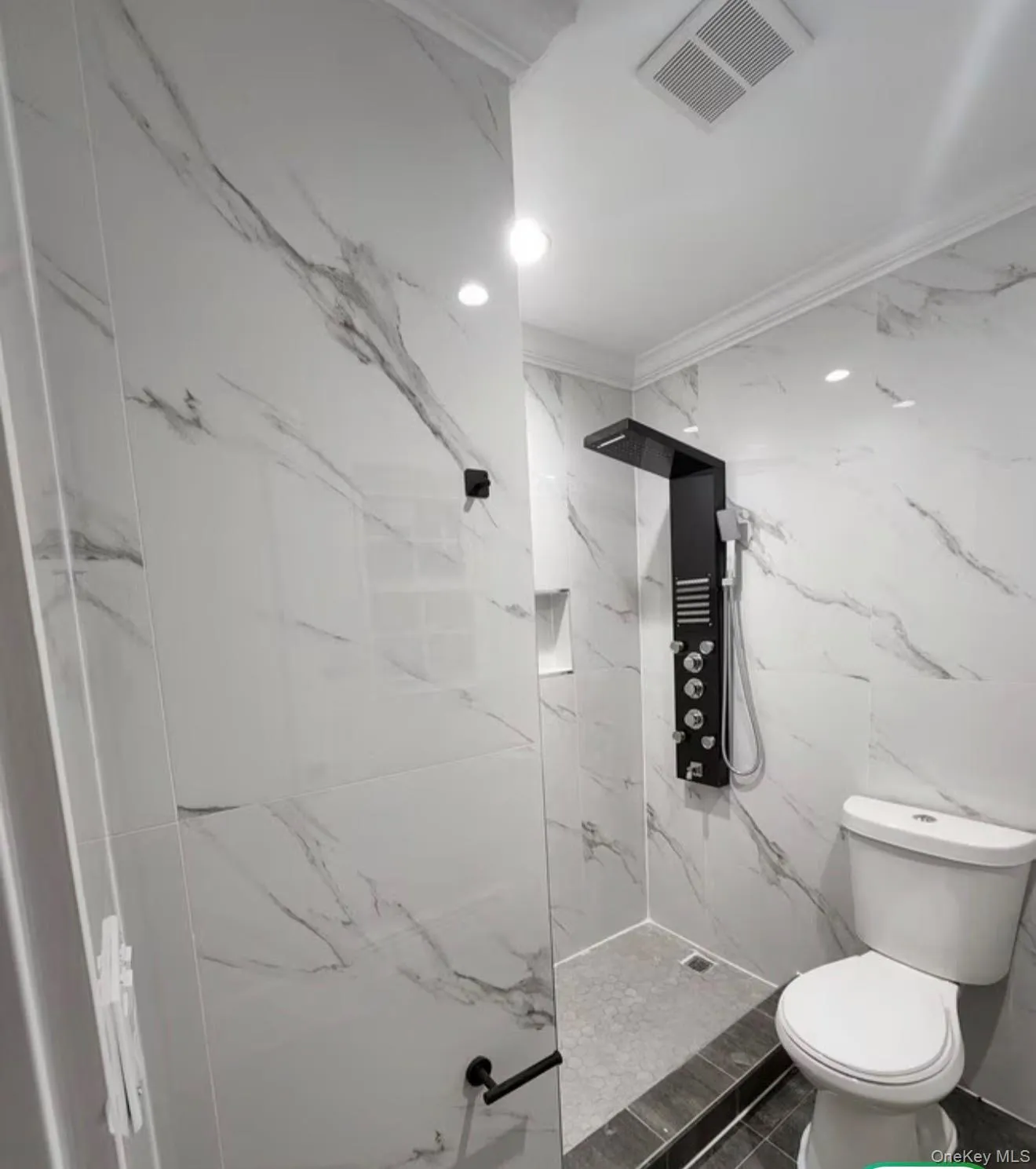 Walk-in shower with full-height tile surround, matte black multi-function shower panel, and glass enclosure Walk-in shower with full-height tile surround, matte black multi-function shower panel, and glass enclosure