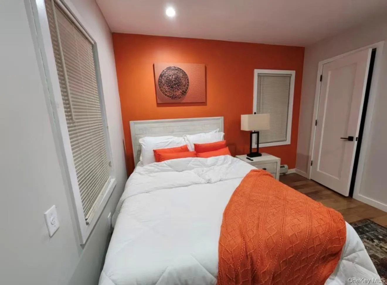 Painted accent wall with recessed lighting, wood-finish flooring, and white interior door with black hardware Painted accent wall with recessed lighting, wood-finish flooring, and white interior door with black hardware