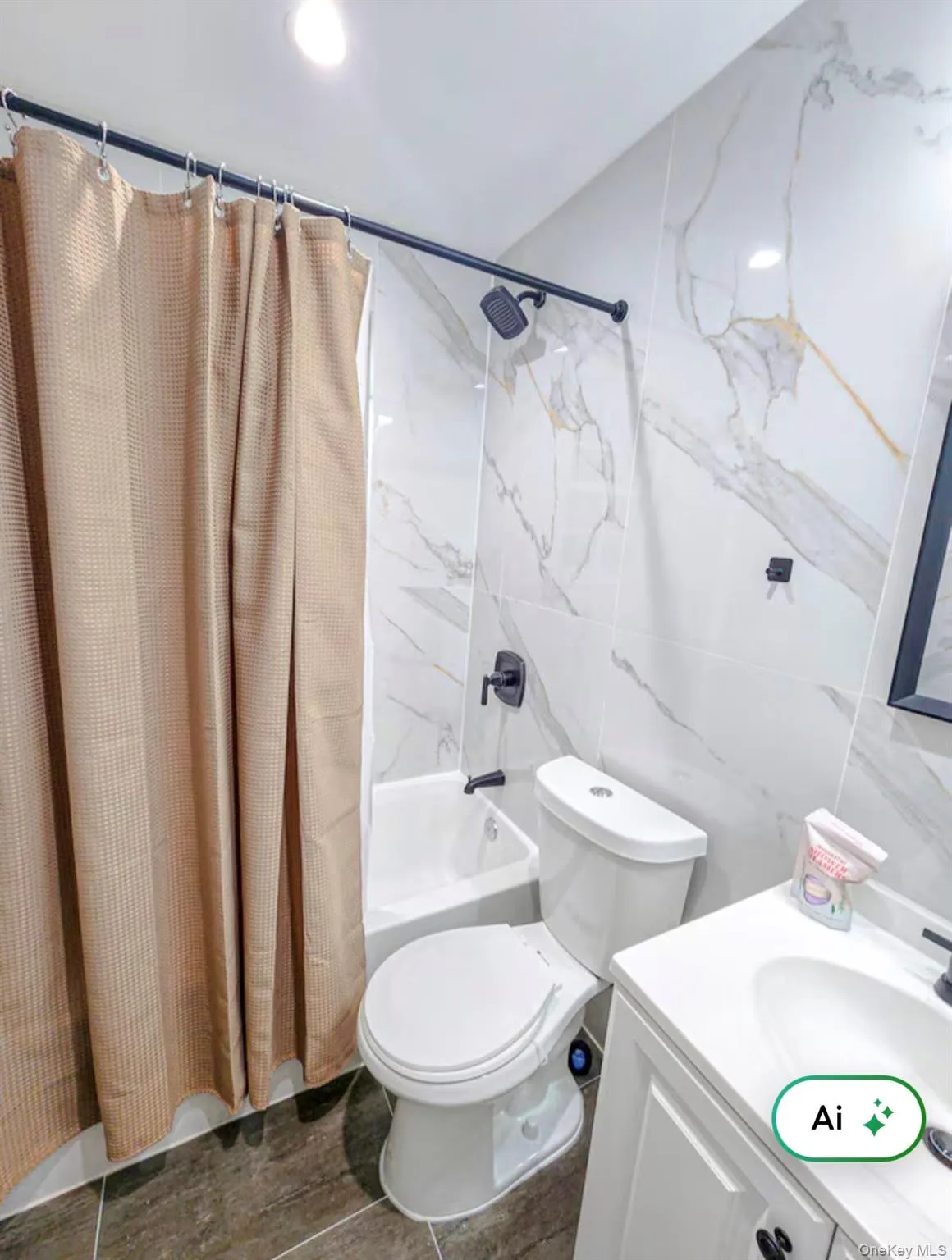 Bathtub with matte black fixtures, white toilet, white vanity with integrated sink, and large format wall tile Bathtub with matte black fixtures, white toilet, white vanity with integrated sink, and large format wall tile