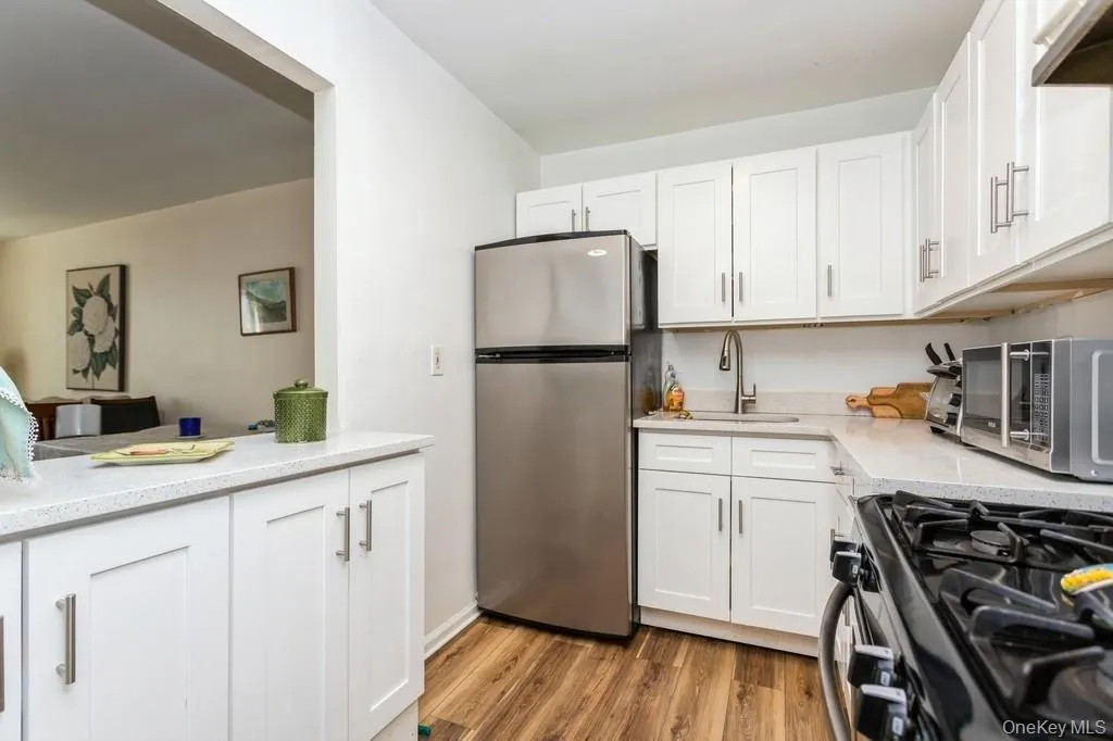 Kitchen featuring white cabinets, gas stove, a sink, freestanding refrigerator, and light wood-style flooring Kitchen featuring white cabinets, gas stove, a sink, freestanding refrigerator, and light wood-style flooring