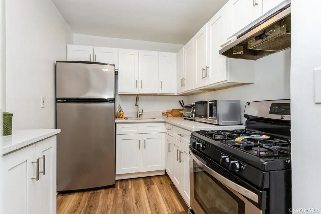 Kitchen featuring white cabinets, a sink, appliances with stainless steel finishes, and under cabinet range hood Kitchen featuring white cabinets, a sink, appliances with stainless steel finishes, and under cabinet range hood