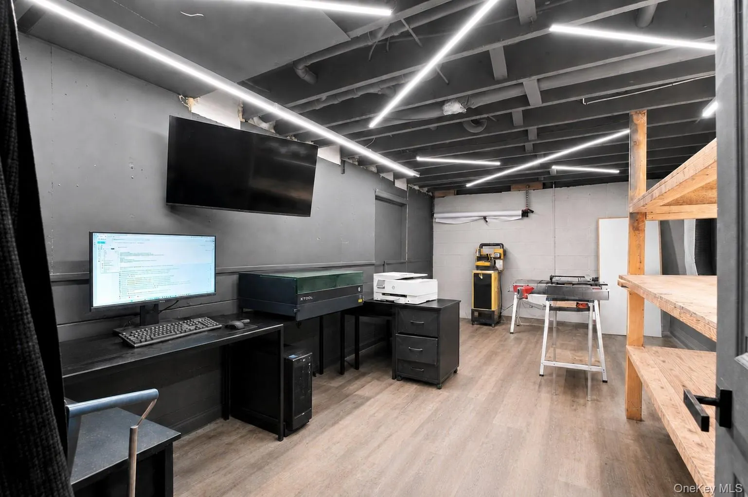 Recessed ceiling lighting, painted exposed ceiling joists, wood-finish flooring, built-in wooden shelving, and a wall-mounted display Recessed ceiling lighting, painted exposed ceiling joists, wood-finish flooring, built-in wooden shelving, and a wall-mounted display