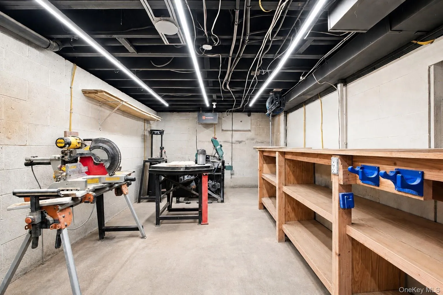 Concrete block walls with a concrete floor, featuring built-in wooden shelving and overhead linear lighting fixtures Concrete block walls with a concrete floor, featuring built-in wooden shelving and overhead linear lighting fixtures