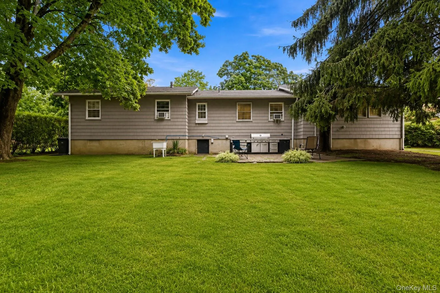 Expansive green lawn with mature trees and a rear patio Expansive green lawn with mature trees and a rear patio