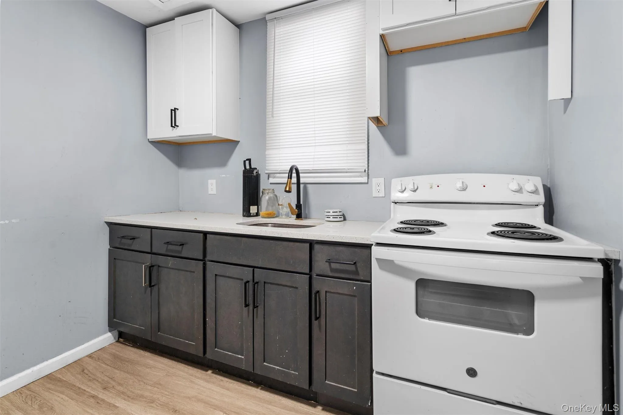 Kitchen featuring light hardwood / wood-style flooring, dark brown cabinets, white range with electric cooktop, white cabinets, and sink Kitchen featuring light hardwood / wood-style flooring, dark brown cabinets, white range with electric cooktop, white cabinets, and sink
