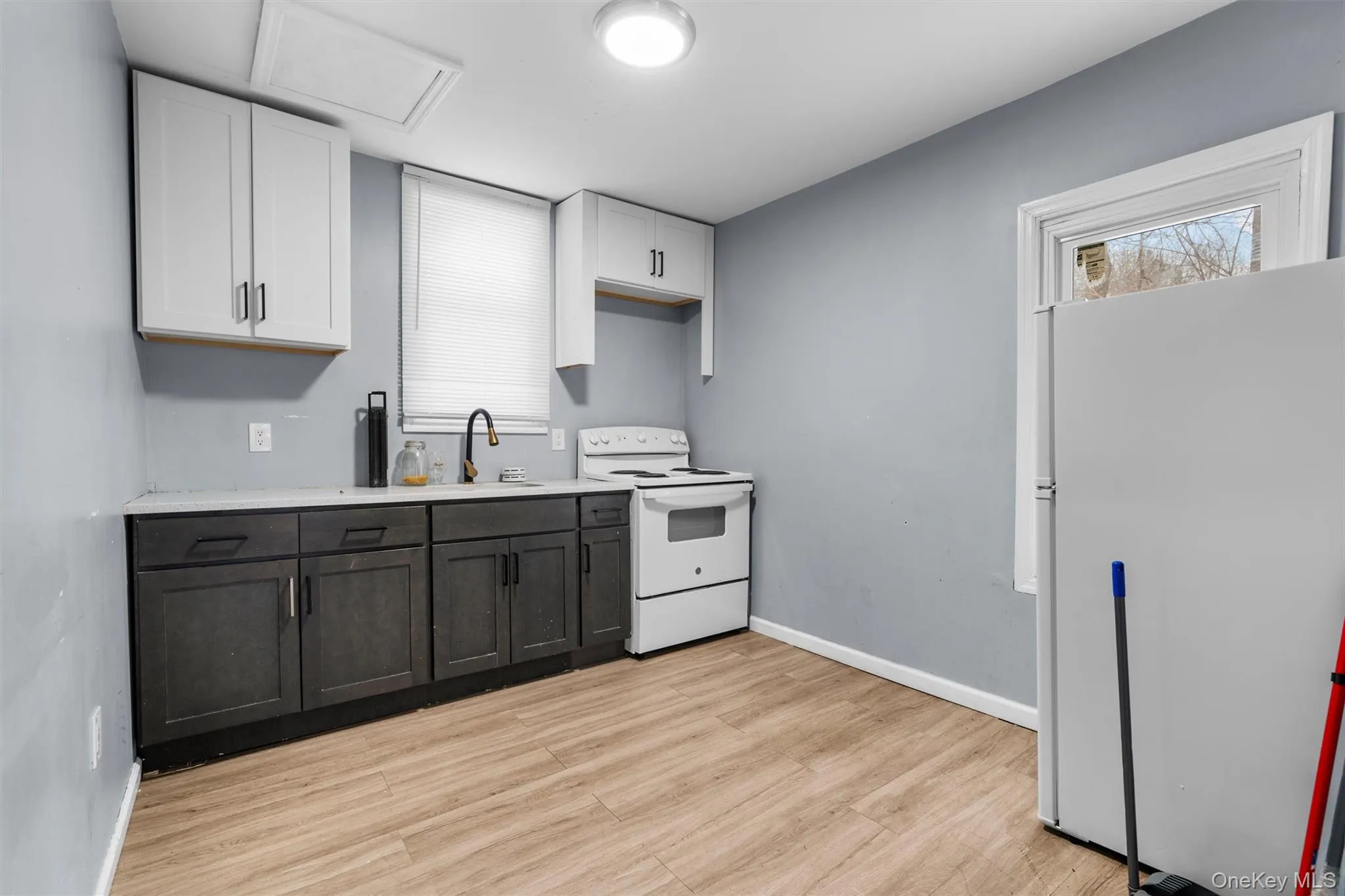 Kitchen with white appliances, light hardwood / wood-style floors, white cabinetry, and sink Kitchen with white appliances, light hardwood / wood-style floors, white cabinetry, and sink