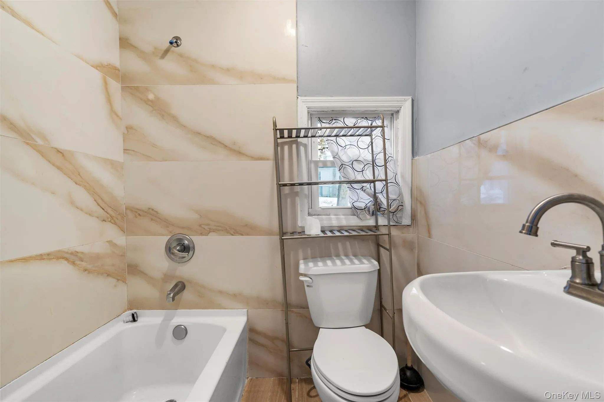 Bathroom with sink, tile walls, a tub to relax in, and toilet Bathroom with sink, tile walls, a tub to relax in, and toilet