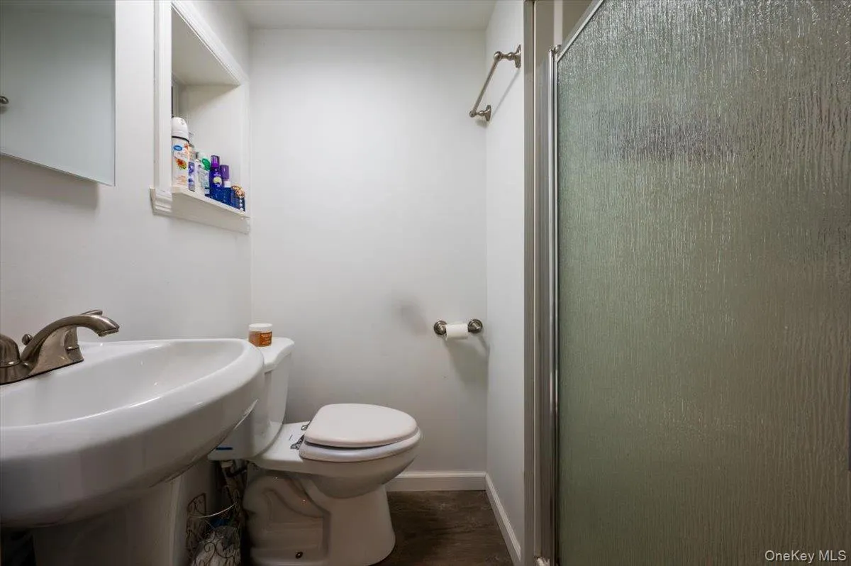 Bathroom featuring toilet, a shower with door, and sink Bathroom featuring toilet, a shower with door, and sink