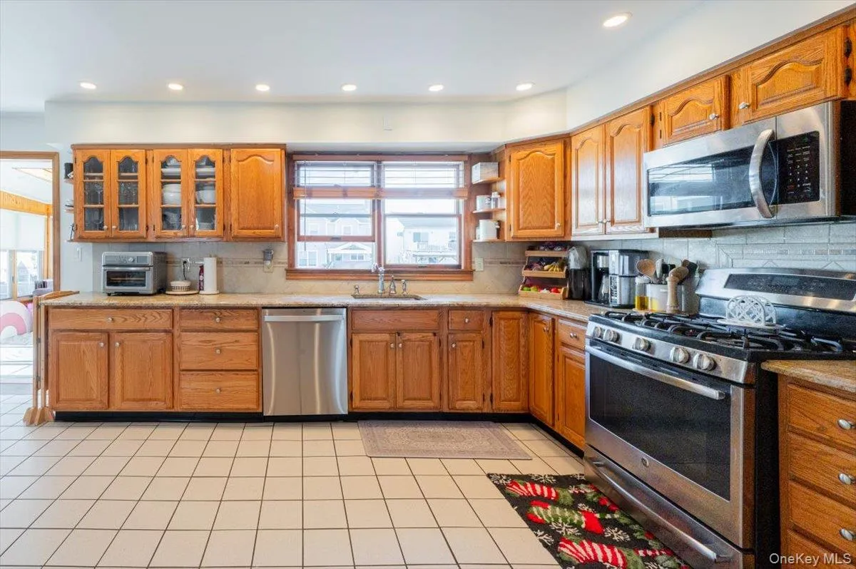Kitchen featuring light tile patterned floors, backsplash, stainless steel appliances, and sink Kitchen featuring light tile patterned floors, backsplash, stainless steel appliances, and sink