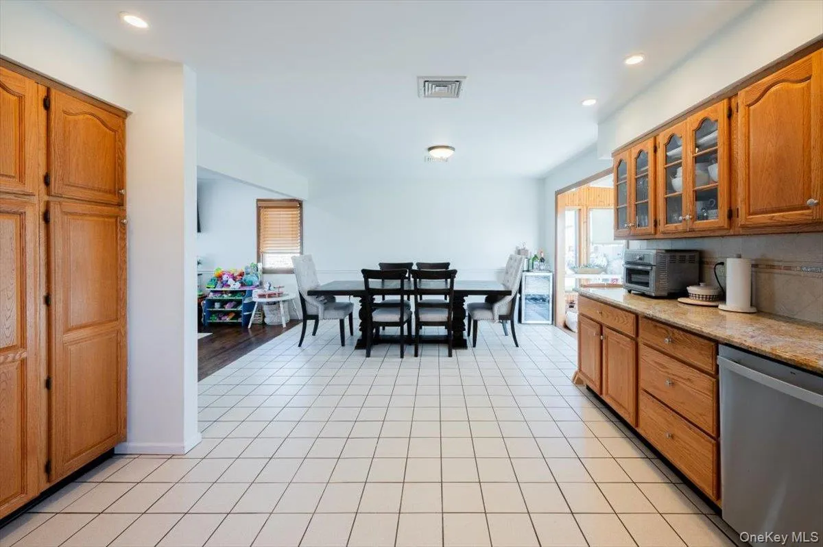 Kitchen with decorative backsplash, dishwasher, and light hardwood / wood-style floors Kitchen with decorative backsplash, dishwasher, and light hardwood / wood-style floors