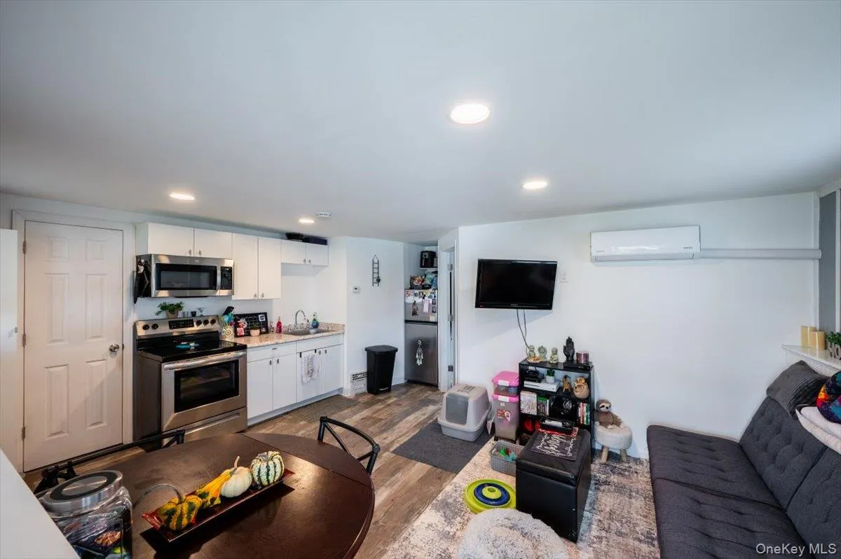 Living room with light wood-type flooring, an AC wall unit, and sink Living room with light wood-type flooring, an AC wall unit, and sink