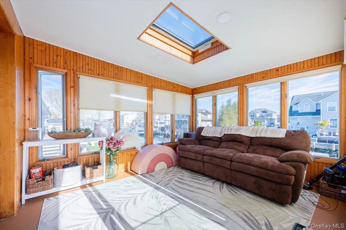 Living room with vaulted ceiling with skylight, a wealth of natural light, and wood walls Living room with vaulted ceiling with skylight, a wealth of natural light, and wood walls