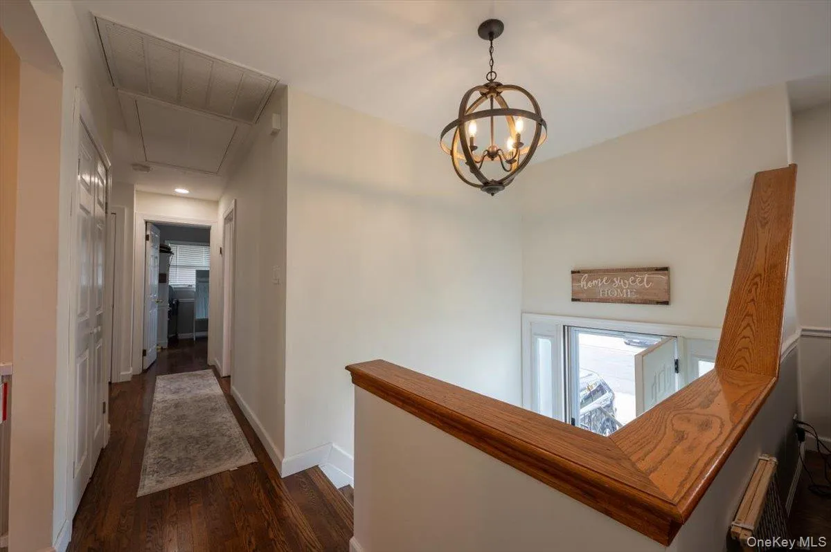 Hall with radiator heating unit, dark hardwood / wood-style floors, and an inviting chandelier Hall with radiator heating unit, dark hardwood / wood-style floors, and an inviting chandelier