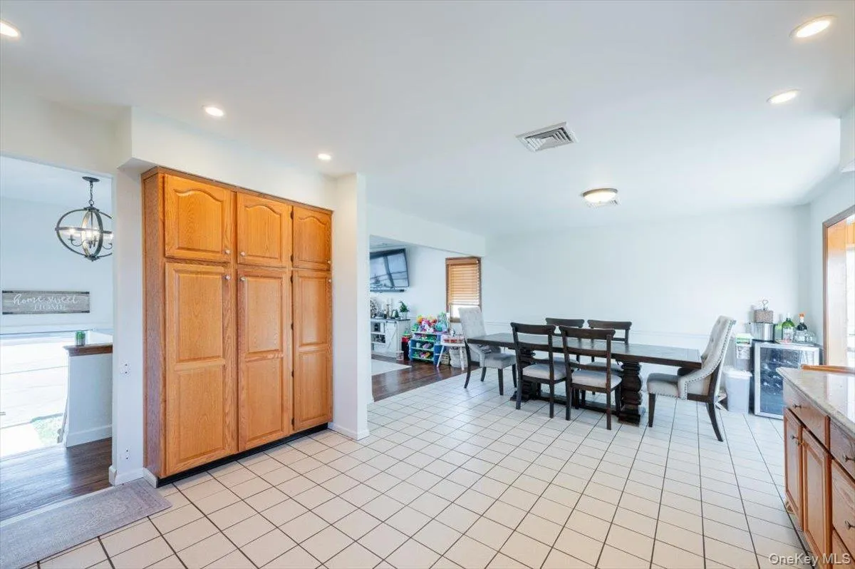 Kitchen featuring light wood-type flooring, hanging light fixtures, wine cooler, and an inviting chandelier Kitchen featuring light wood-type flooring, hanging light fixtures, wine cooler, and an inviting chandelier
