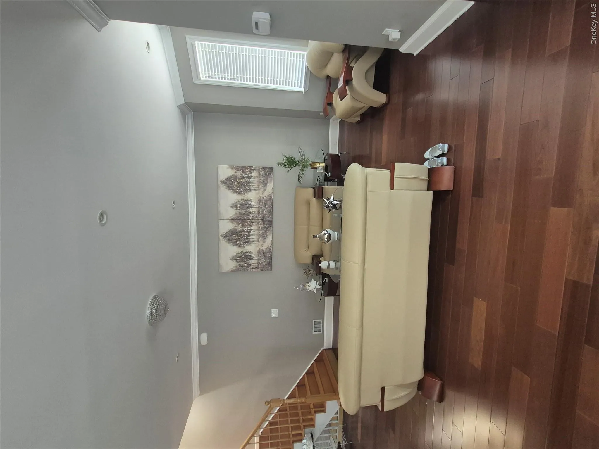 Spacious living room area with hardwood flooring, recessed lighting, crown molding, and a large window with blinds Spacious living room area with hardwood flooring, recessed lighting, crown molding, and a large window with blinds