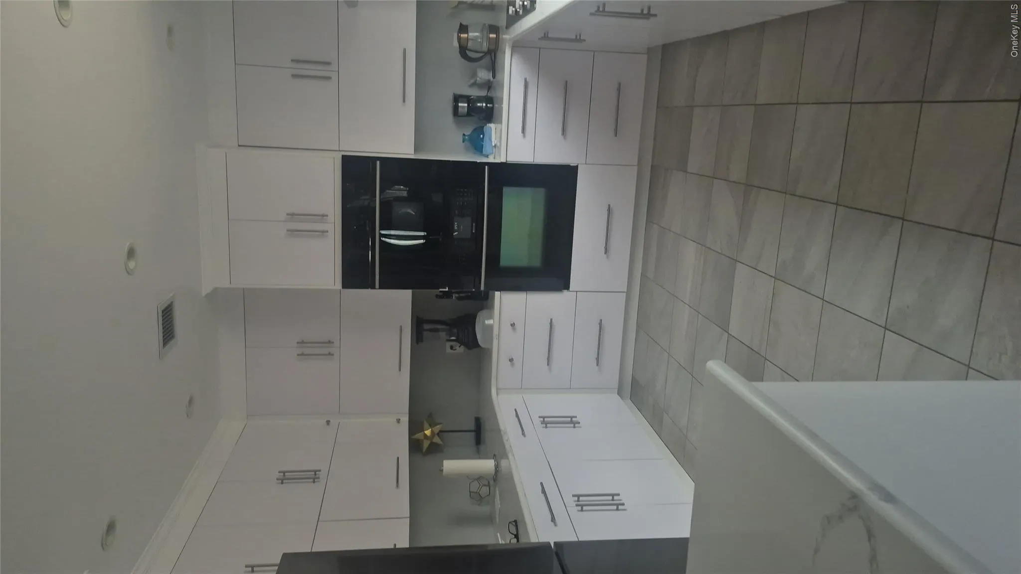 White cabinetry, stone-finish countertops, tile flooring, built-in wall oven, and built-in microwave and dishwasher White cabinetry, stone-finish countertops, tile flooring, built-in wall oven, and built-in microwave and dishwasher
